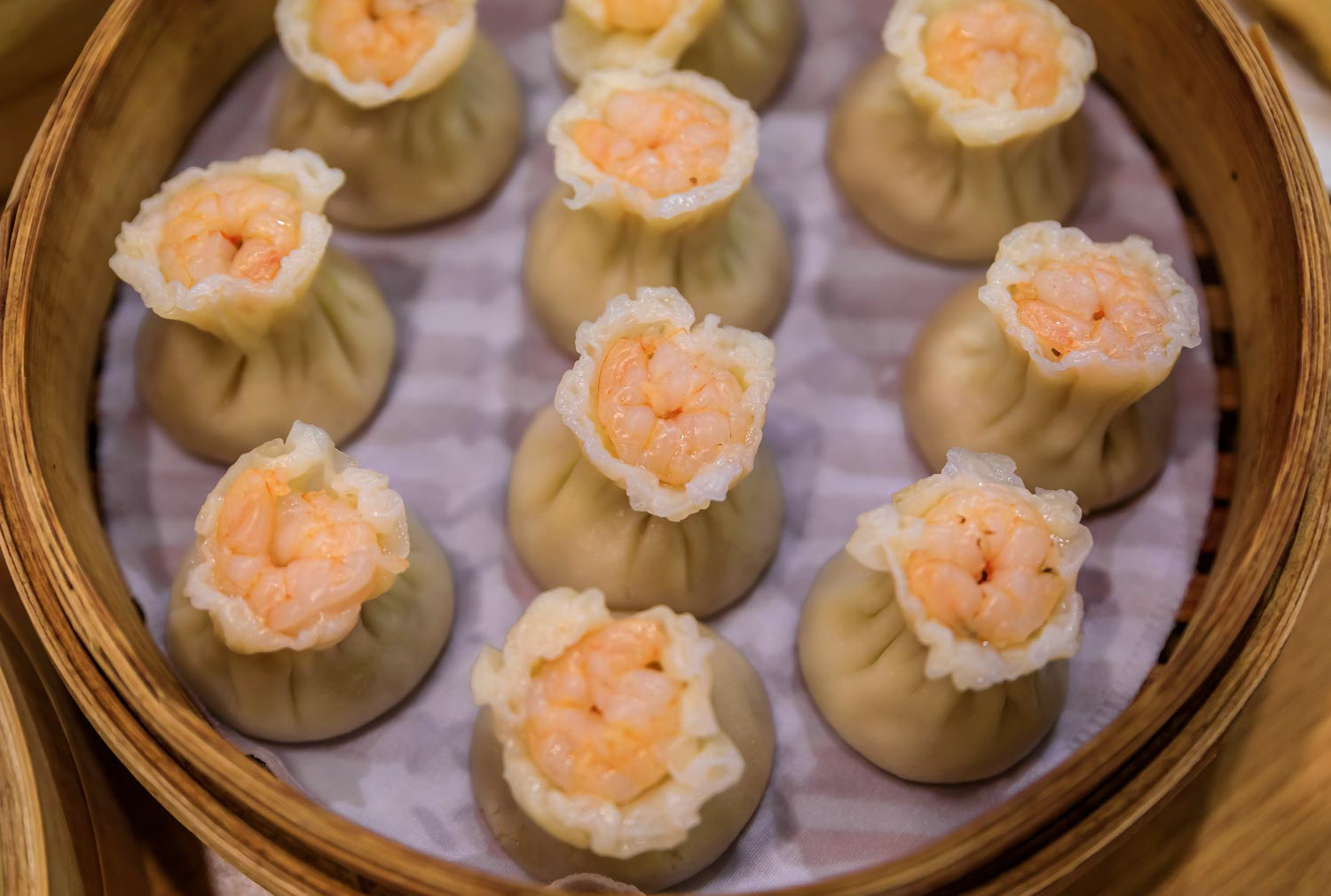 Traditional steamed Chinese har gow dumplings with shrimp and pork in a steamer basket at a restaurant in Singapore