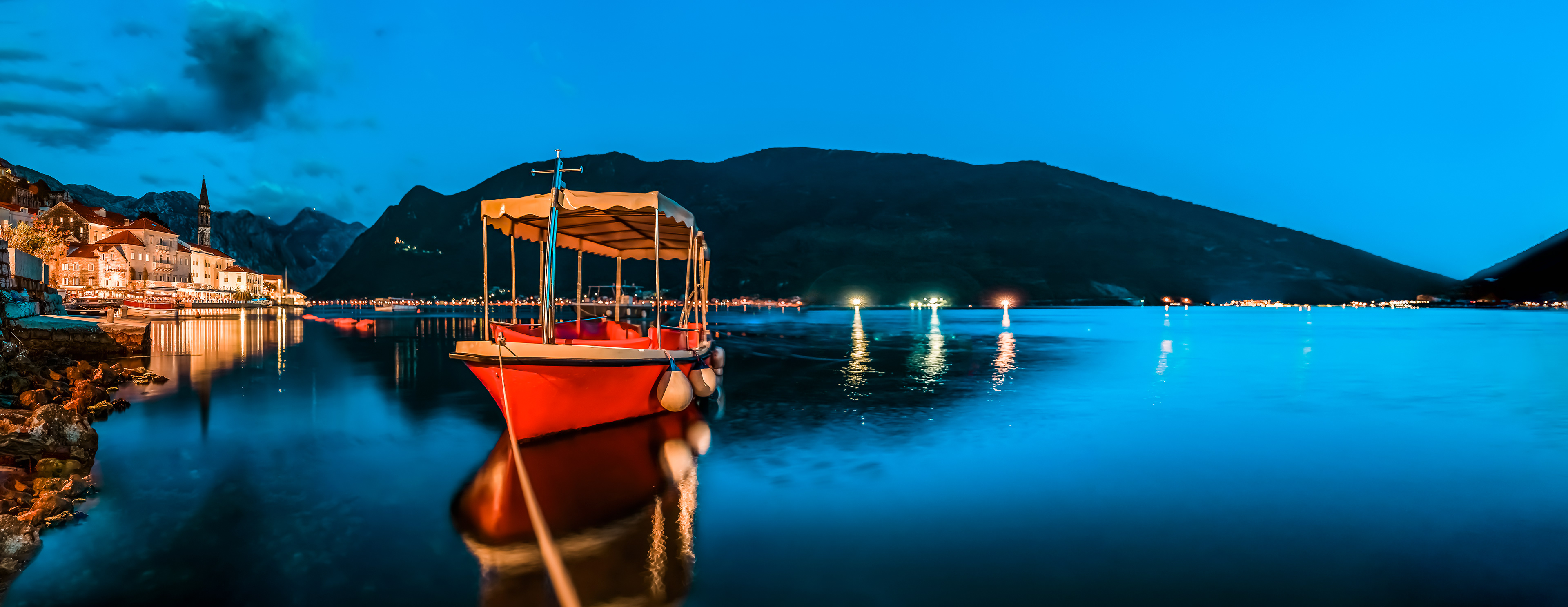 Sunset panorama of Kotor Bay and a docked boat in the town of Perast, Montenegro
