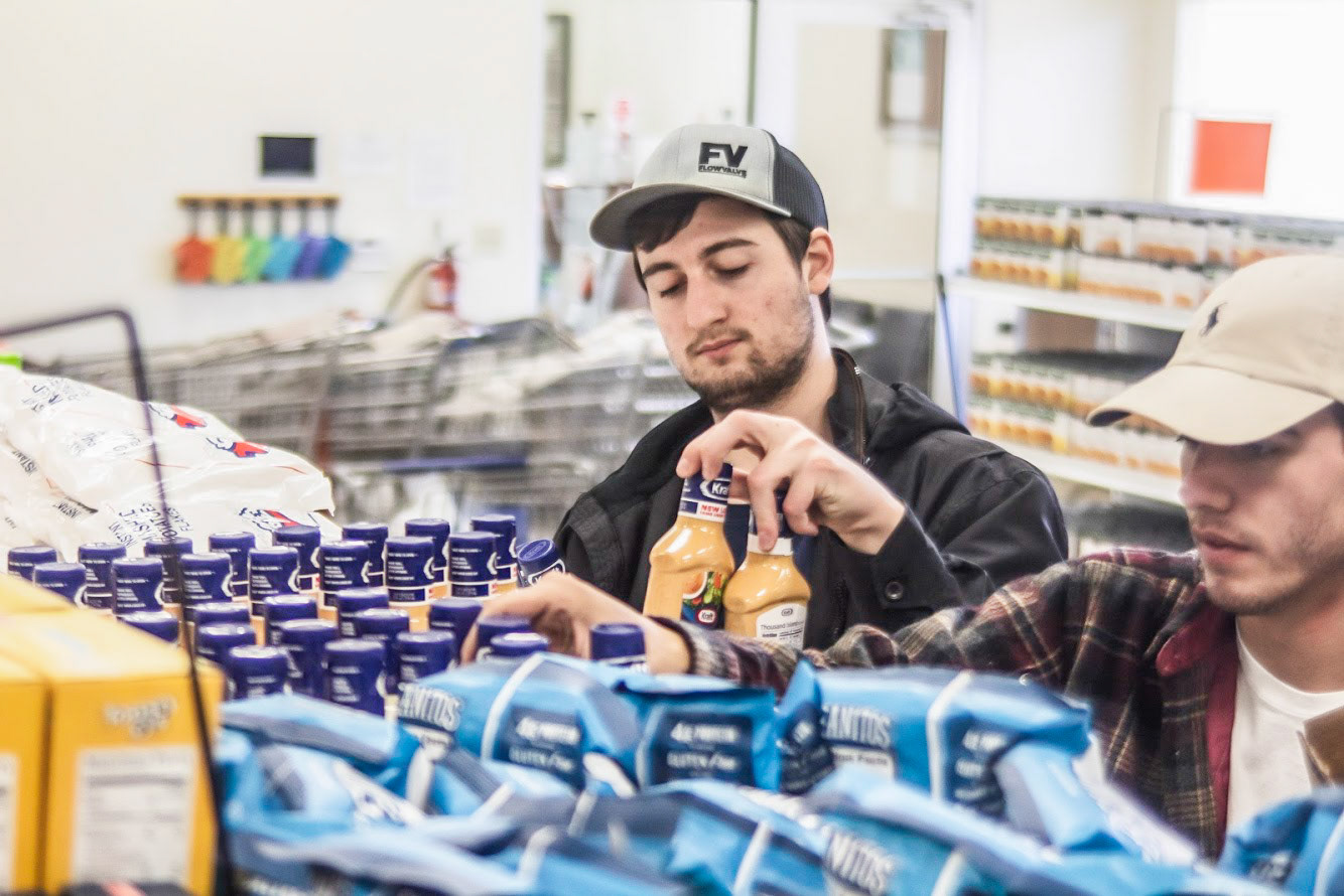 Hudson Payne shelves goods at Shawnee's Comunity Marketduring OBU's annual One Body United community service event. (The Bison)