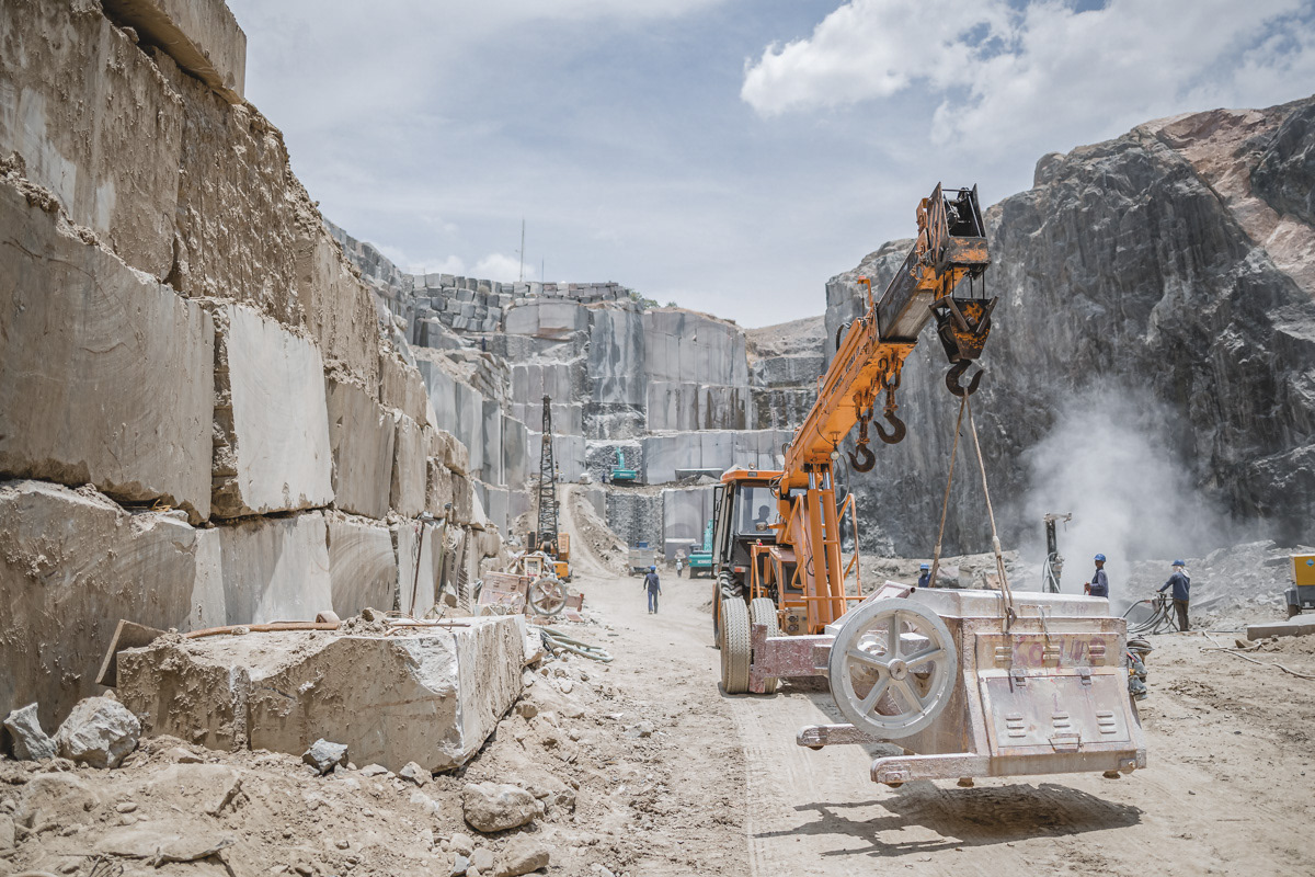 Crane moving heavy drilling machinery in a quarry