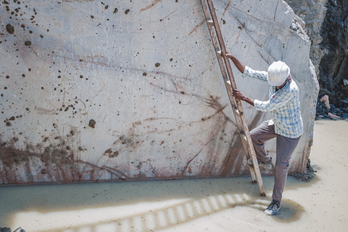Quarry worker navigating through puddle while descending from ladder