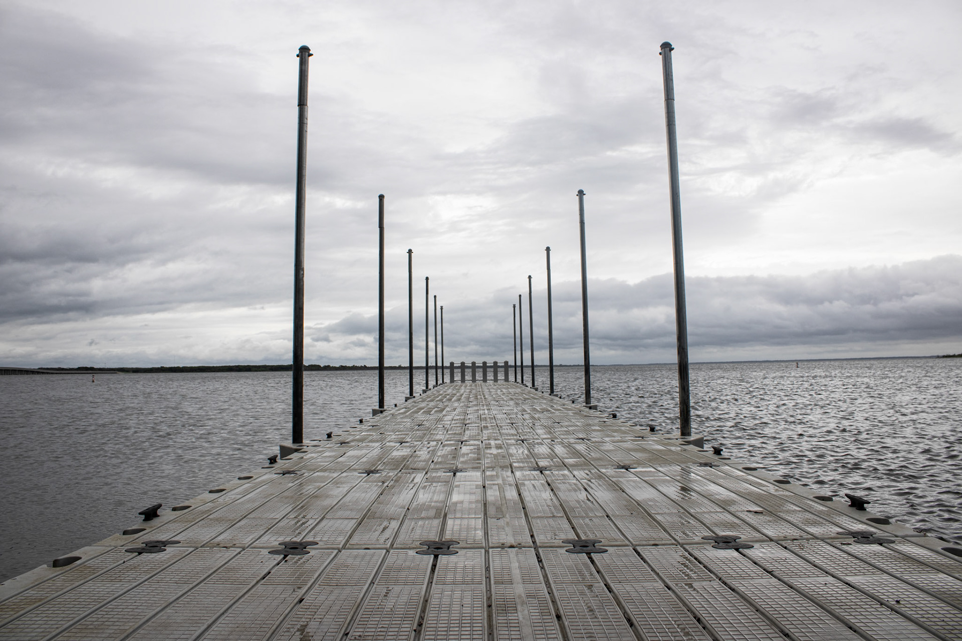 Long dock extending into calm water beneath an overcast sky creating strong perspective lines.