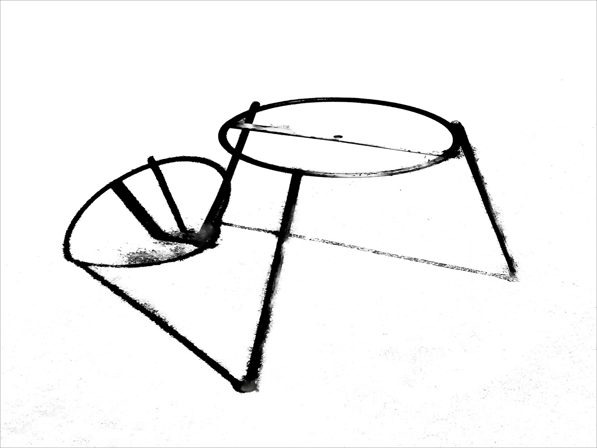 A black circle and its shadow on a blinding white surface, in a minimalist composition.