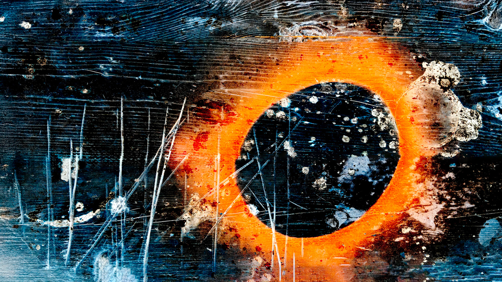 Black circular form surrounded by an orange halo on a scratched, weathered surface with material traces.