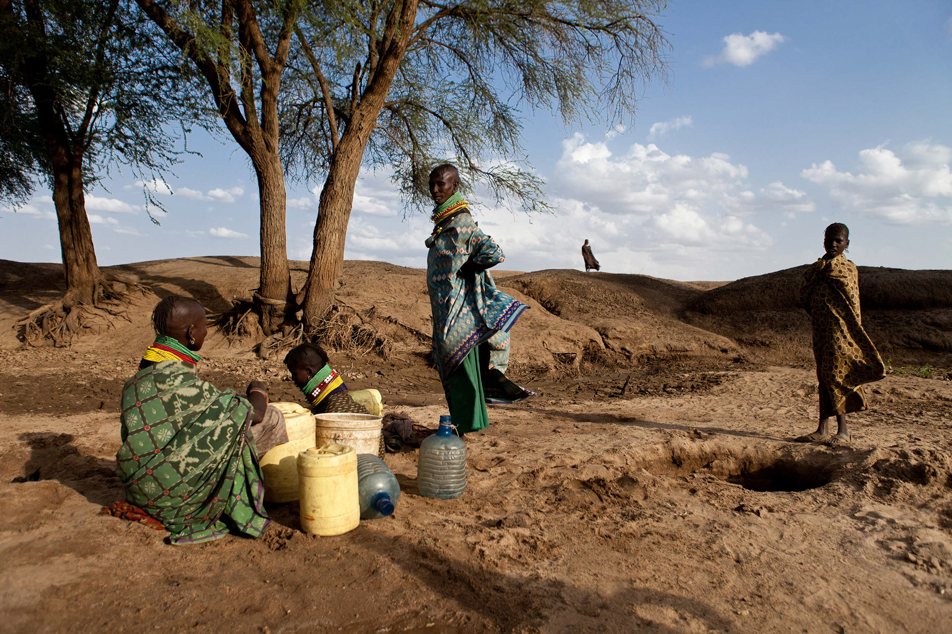 Turkana women dig wells with buckets in dry riverbeds.
