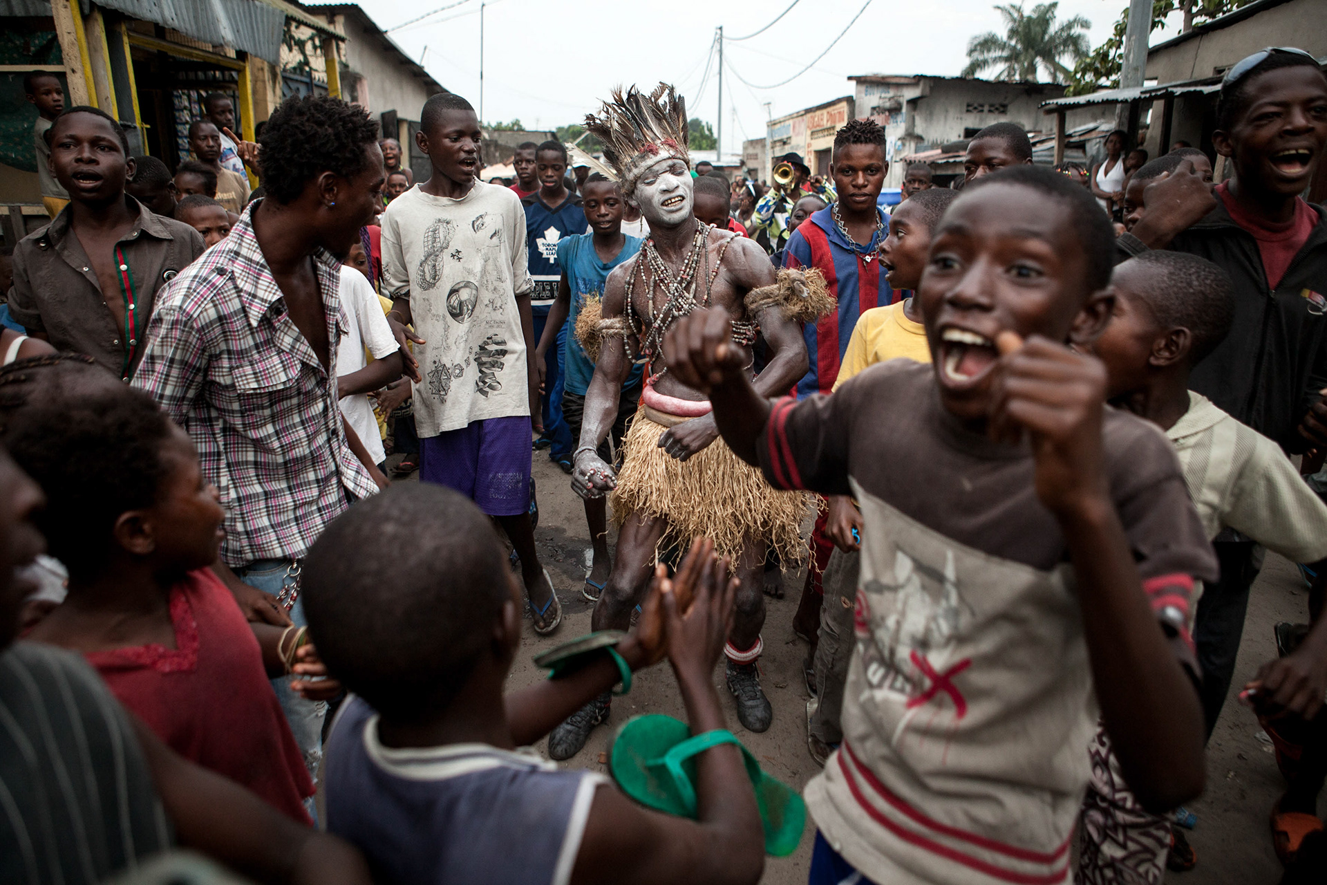 Rafia around the waist and kaolin on the body, Yabeli and the brass band parade in "the city" before a tournament in Ndjili.