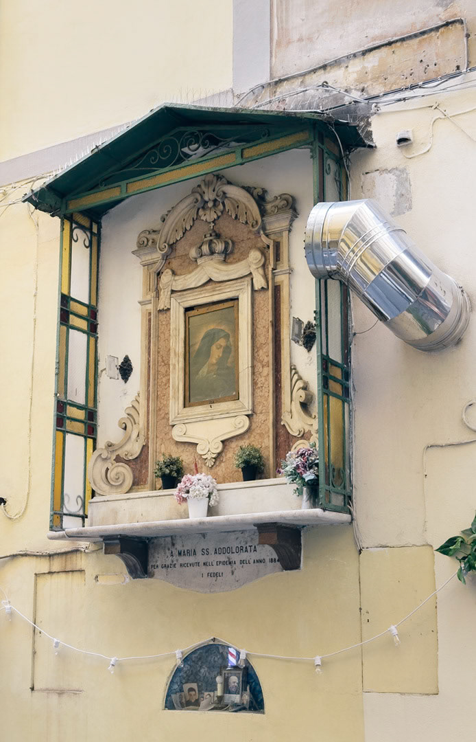 Napoli, Italy - May 27, 2026: Street shrine with sacred icon of Maria Santissima Addolorata on Gradoni di Chiaia, set into a residential facade with flowers, stained glass panels, electrical cables, and urban architectural details.