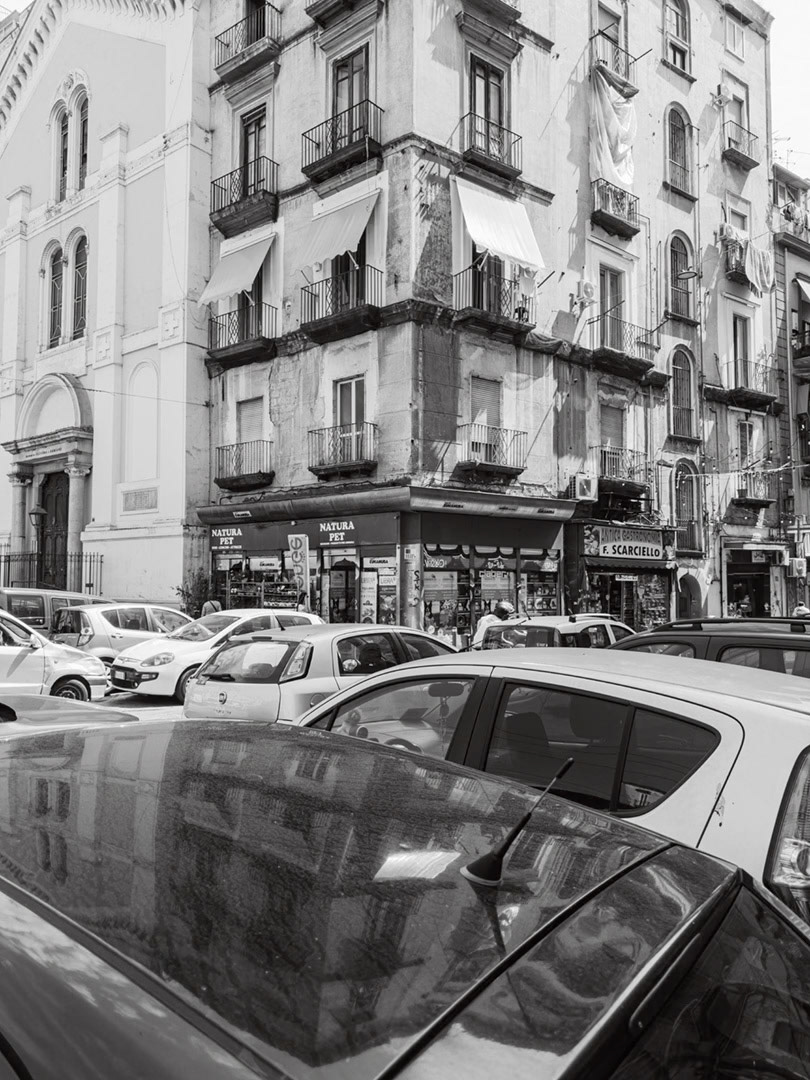 Napoli, Italy - May 28, 2026: Black and white street scene in Piazza Nolana with parked cars, old residential buildings, balconies, hanging laundry, shopfronts, and dense urban life in the historic center of Naples
