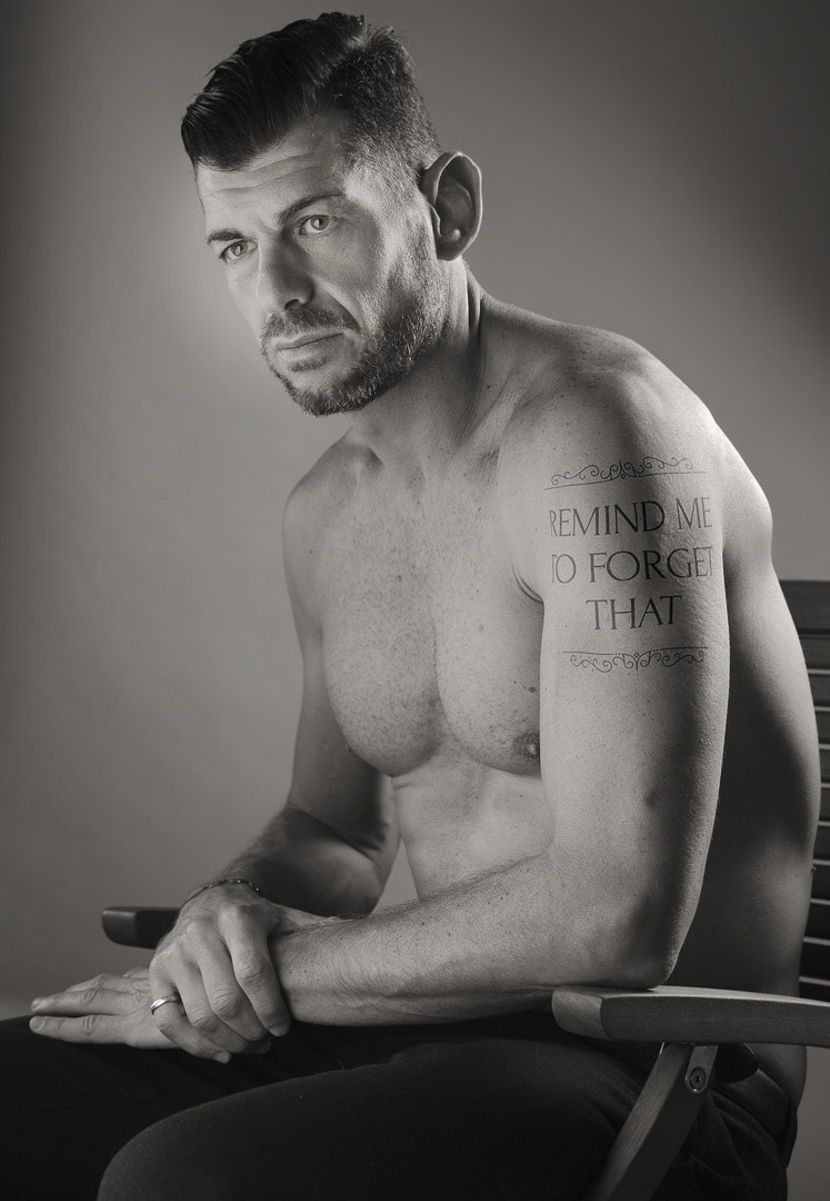 "remind me to forget that" is tattooed on a man's shoulder. *** The artwork was digitally added and a release is provided ***