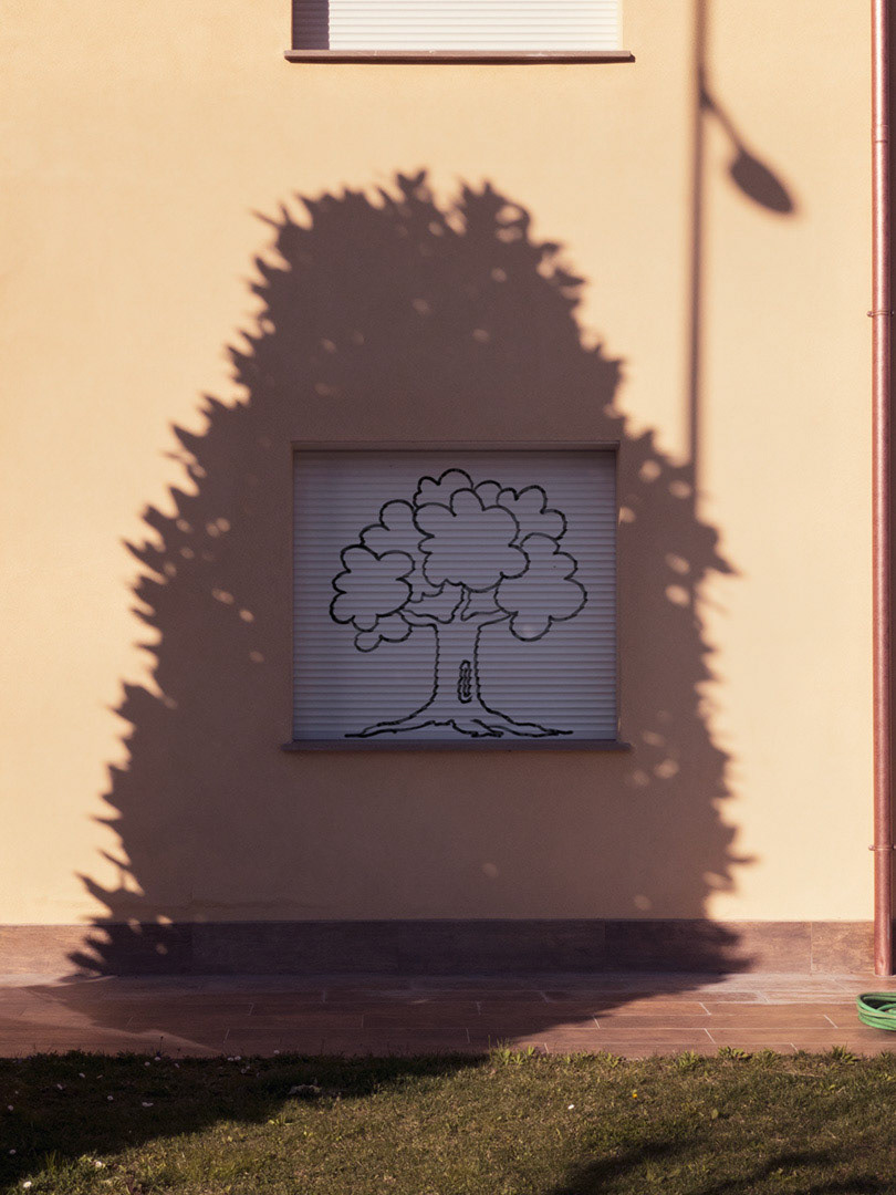 The simple sketch of a tree is drawn on a persiana/rolling shutter that closes the window of a European sunny house. *** The artwork was digitally superimposed and a release is provided ***