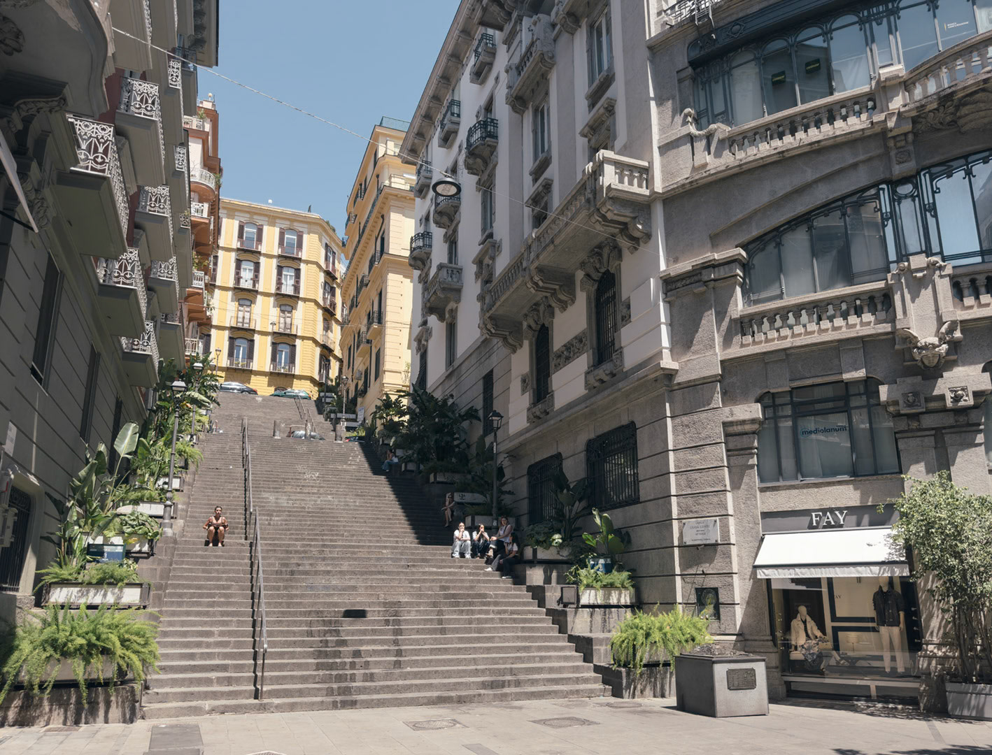 Napoli, Italy - May 27, 2026: View of Gradini Francesco d’Andrea, a broad urban stairway in central Naples framed by elegant historic buildings, balconies, shopfronts, potted greenery, and people resting on the steps