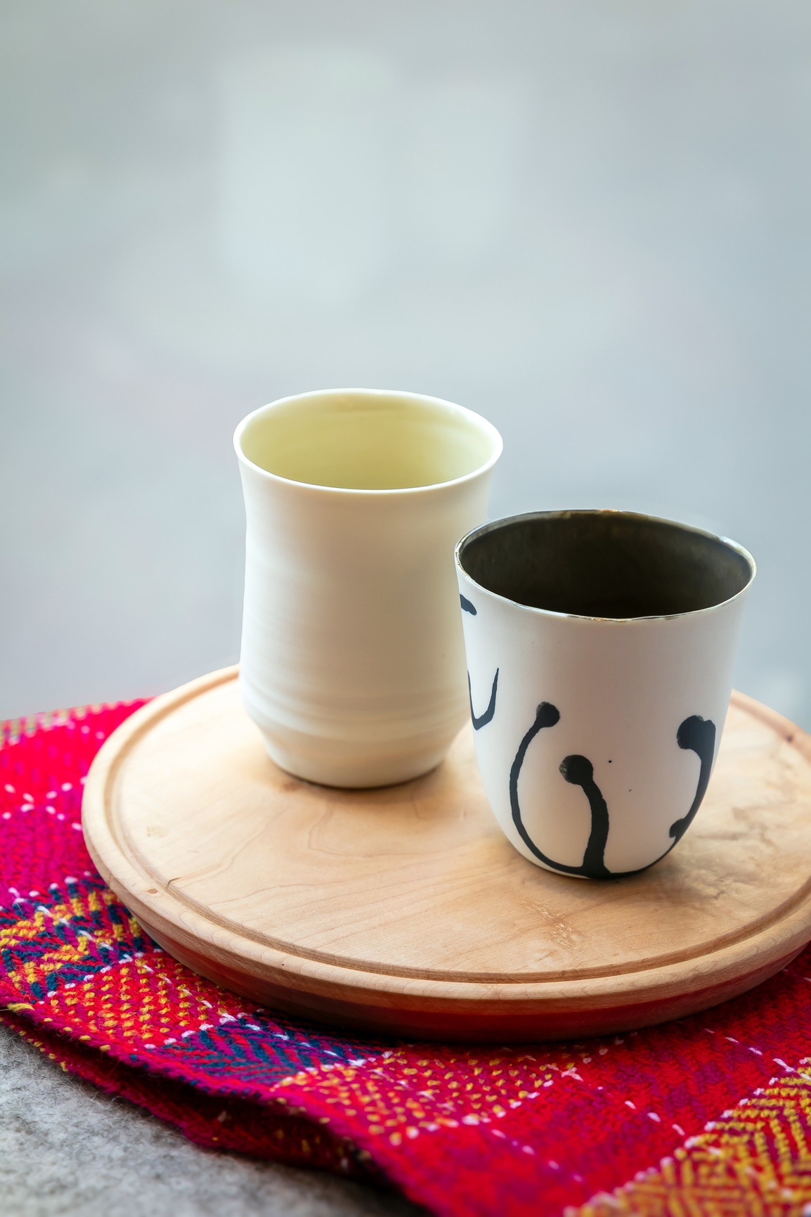 Gobelet "Incorrigible" PM en porcelaine 24€ - Gobelet "Inscrite" PM en porcelaine 22€ - Planche ronde en bois MM 70€ - Maxi Écharpe "Tango" en laine 205€