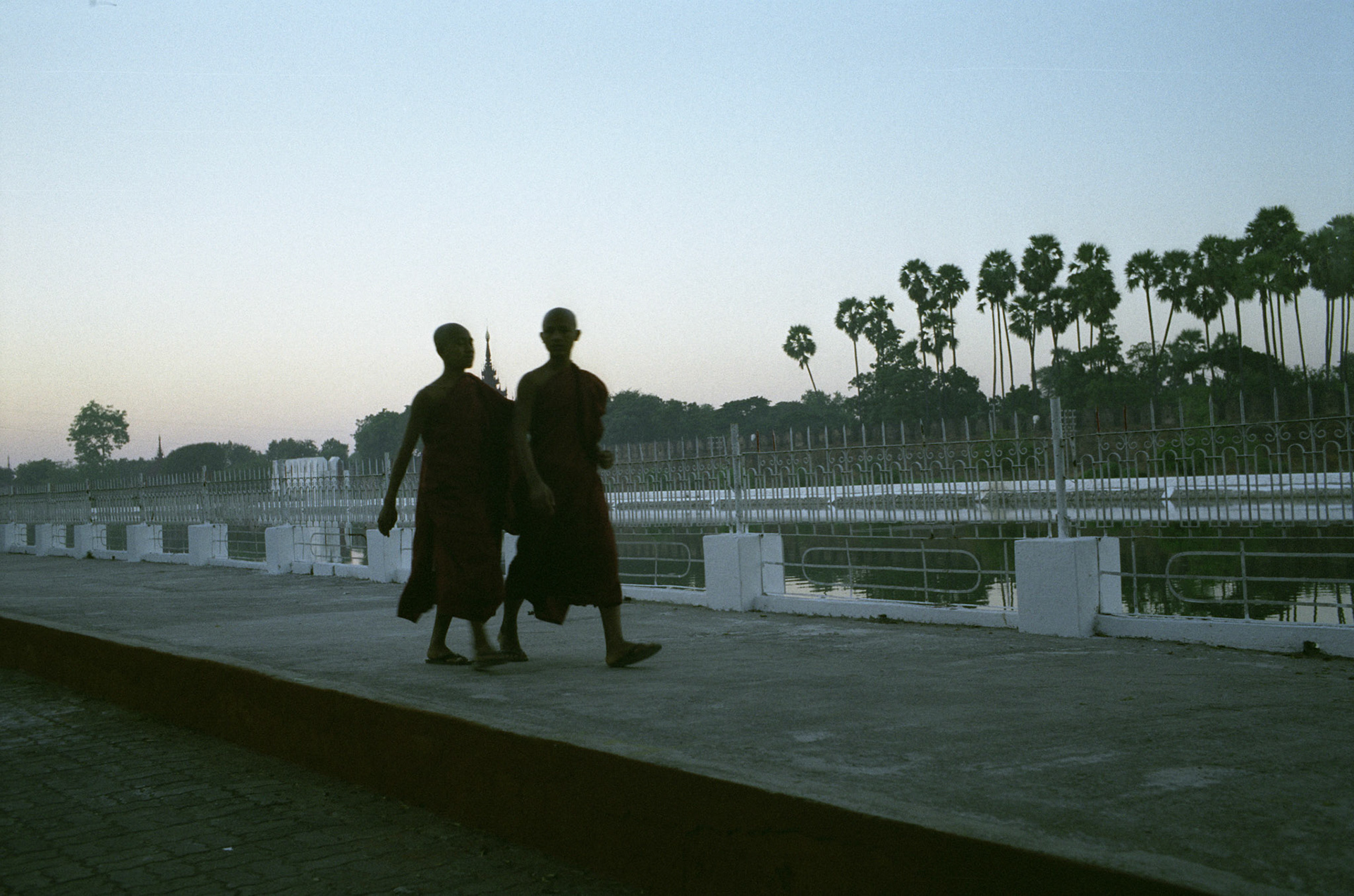 Monks walk beside the moat surrounding Mandalay's Royal Palace and Fort. Considered the center of Burmese culture, Mandalay is an important religious centre, home to thousands of monks