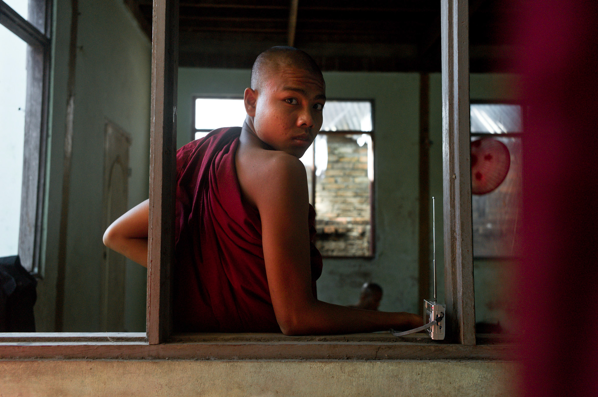 A novice monk now living in Maggin monastery listens to exiled media broadcasts on the radio. On September 26th 2007, at the height of Burma's monk led Saffron Revolution, Maggin Monastery in Rangoon, was raided as the regime commenced its brutal crackdown on the protests. On 13th January 2012 the monks were released from prison and more than four years since the monastery was raided and locked, they returned and opened the doors once more. Everything they found was exactly as it was left the night the military regime arrested them and ransacked the buildings.