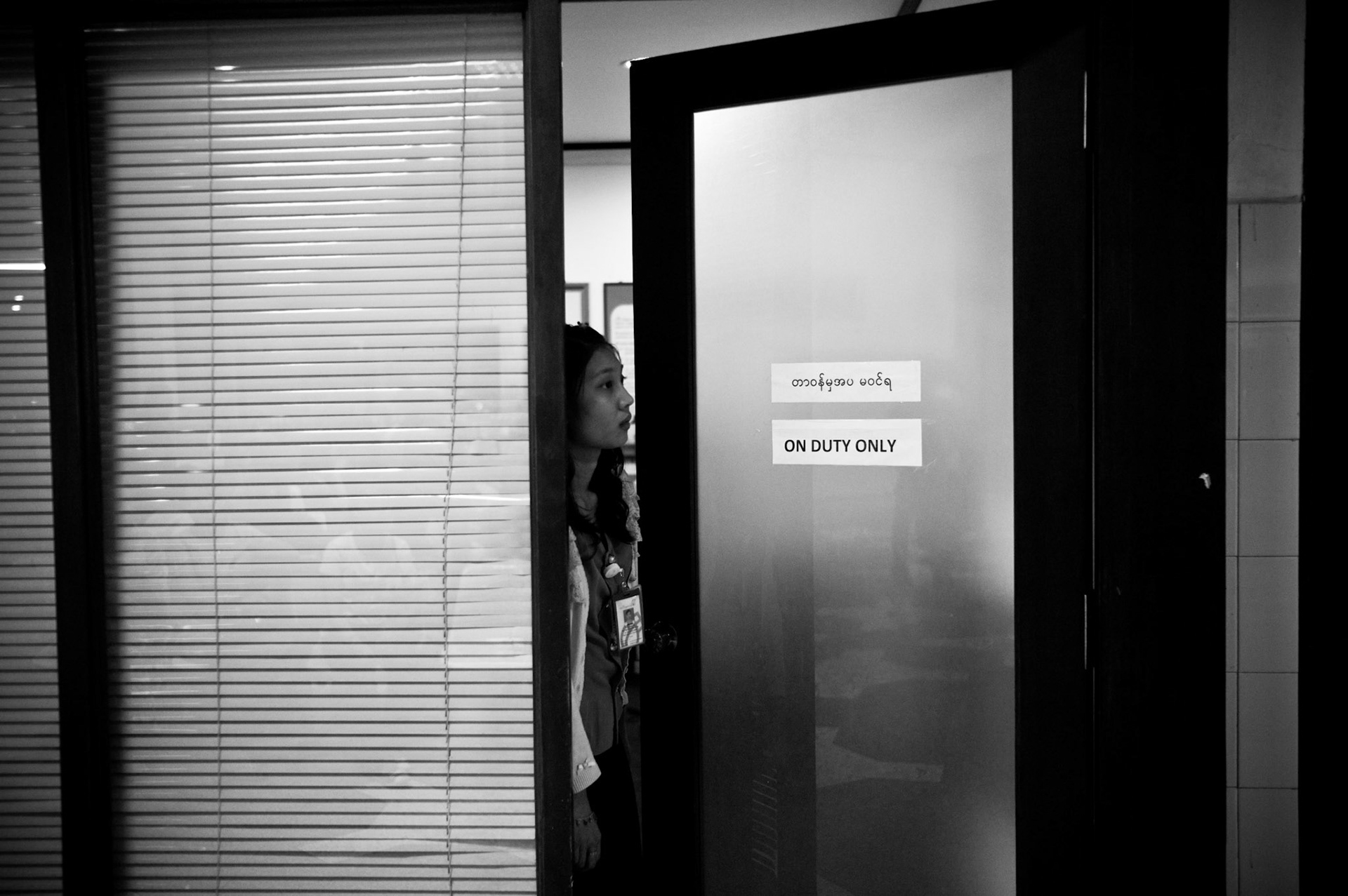 A member of the airport staff looks out of her office as hundreds of people cram into the domestic terminal of Rangoon airport to welcome home the 88 Generation Students. The Presidential amnesty saw more than 600 political prisoners released from prison, many of who were former leaders of the mass democracy uprising in 1988 and were serving long sentences of 65 years or more.