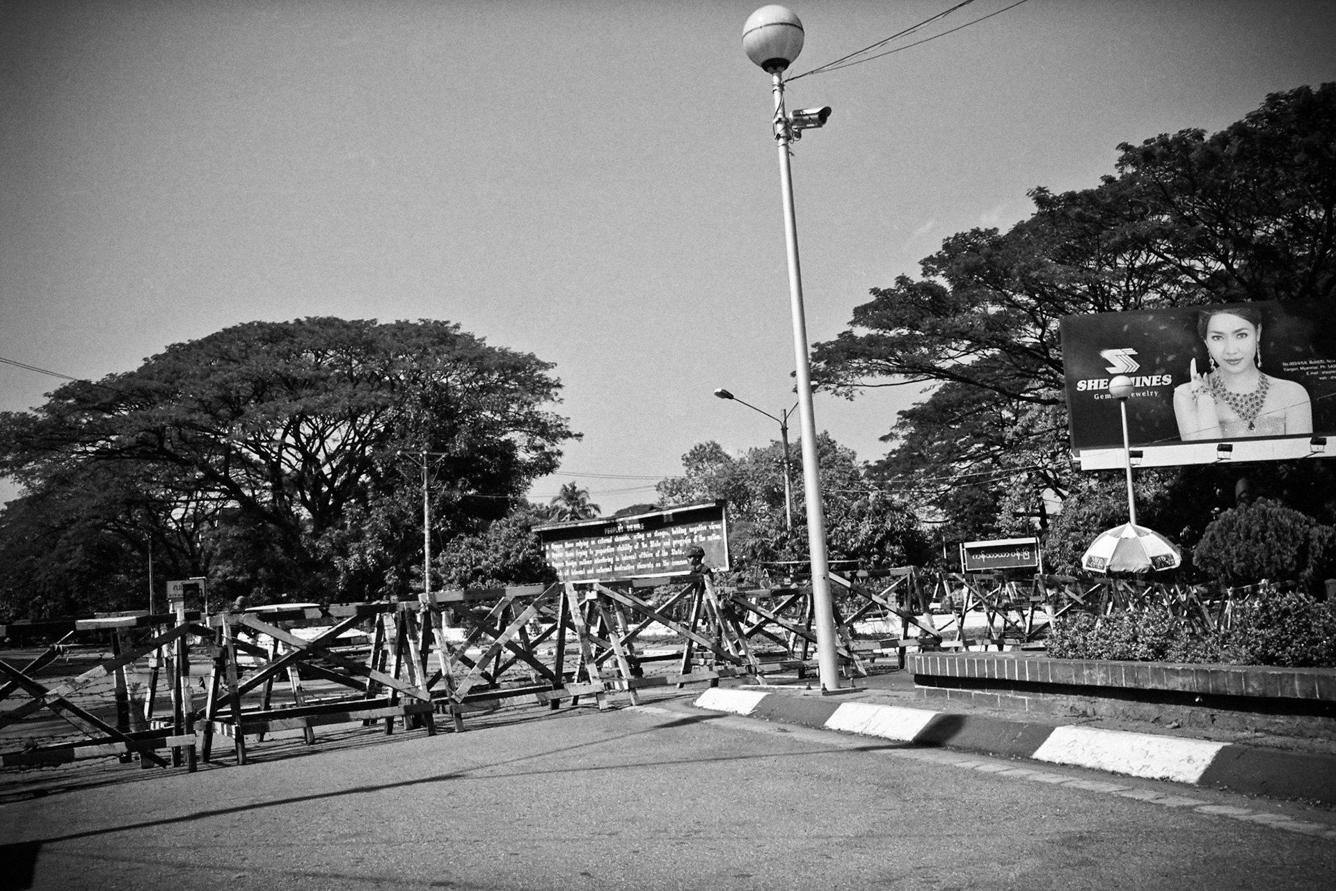 Soldiers keep watch behind blockades on University Avenue, Rangoon, Burma. Since 1989 when Aung San Suu Kyi was first arrested,  Burma's military regime have erected the rudimentary blockades to keep people away from her home.