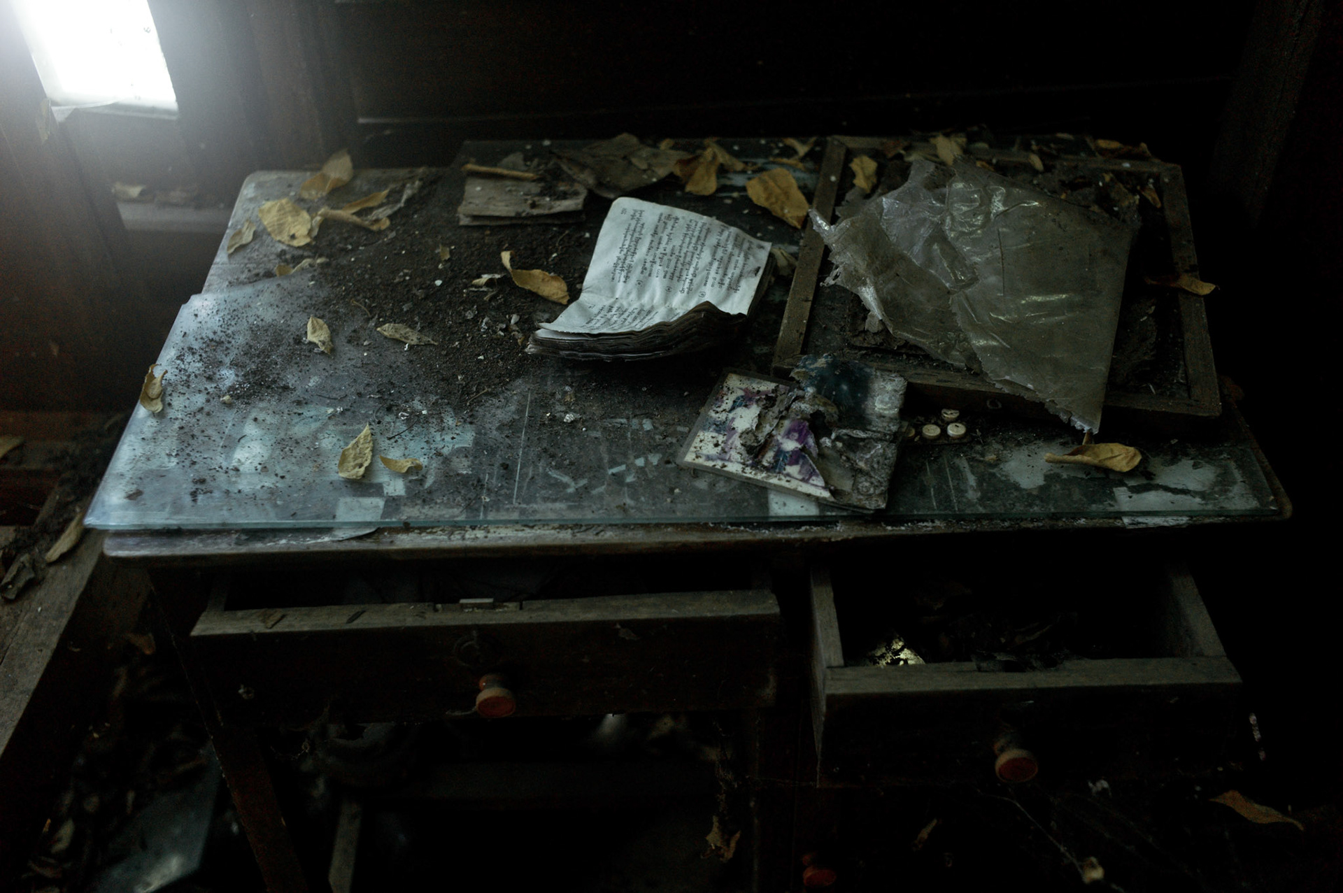 A family photograph and picture frame lie broken and torn on U Eindaka's desk. On September 26th 2007, at the height of Burma's monk led Saffron Revolution, Maggin Monastery in Rangoon, was raided as the regime commenced its brutal crackdown on the protests. On 13th January 2012 the monks were released from prison and more than four years since the monastery was raided and locked, they returned and opened the doors once more. Everything they found was exactly as it was left the night the military regime arrested them and ransacked the buildings.