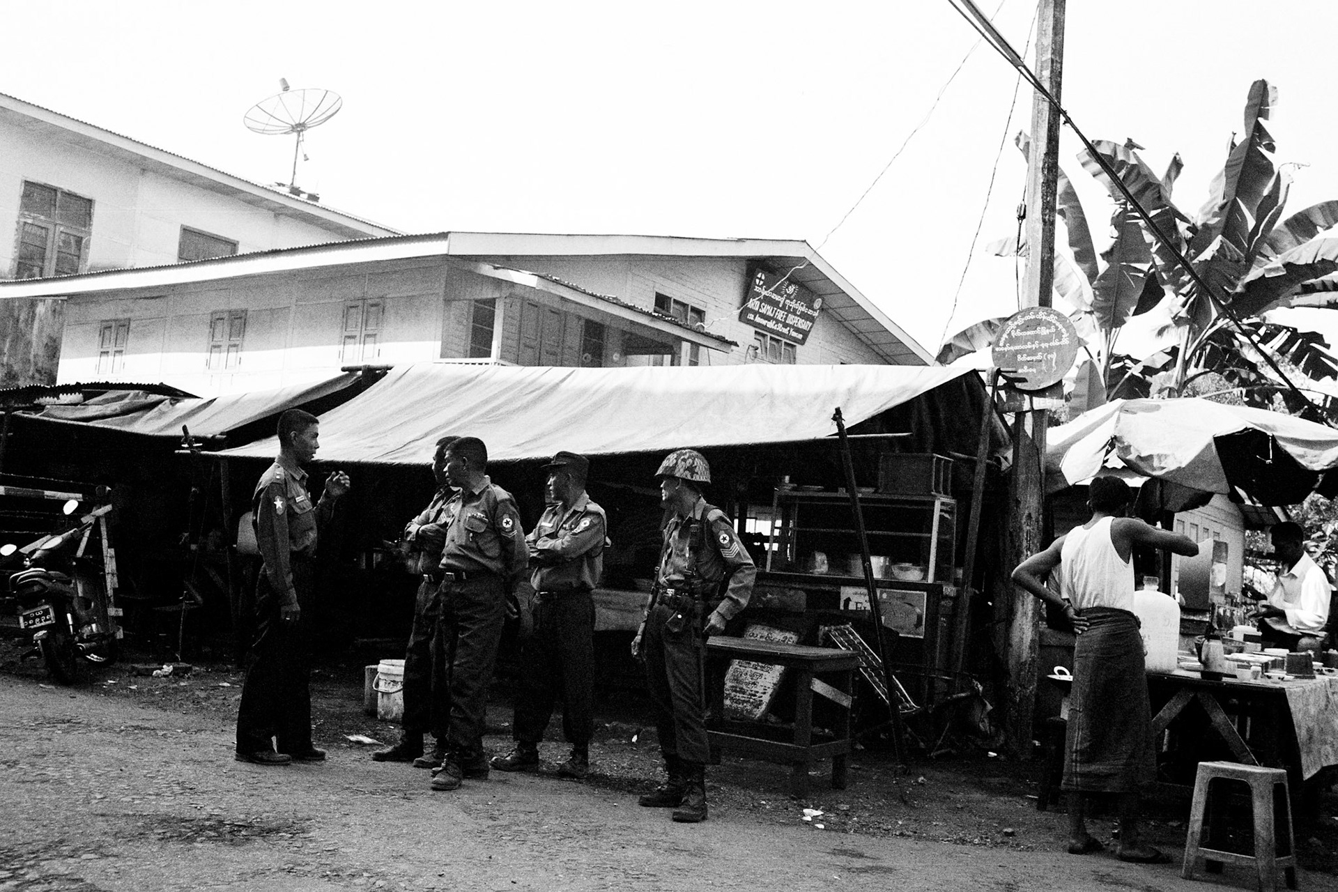 Policemen wait outside a teashop in downtown Rangoon whilst intelligence offiers search inside