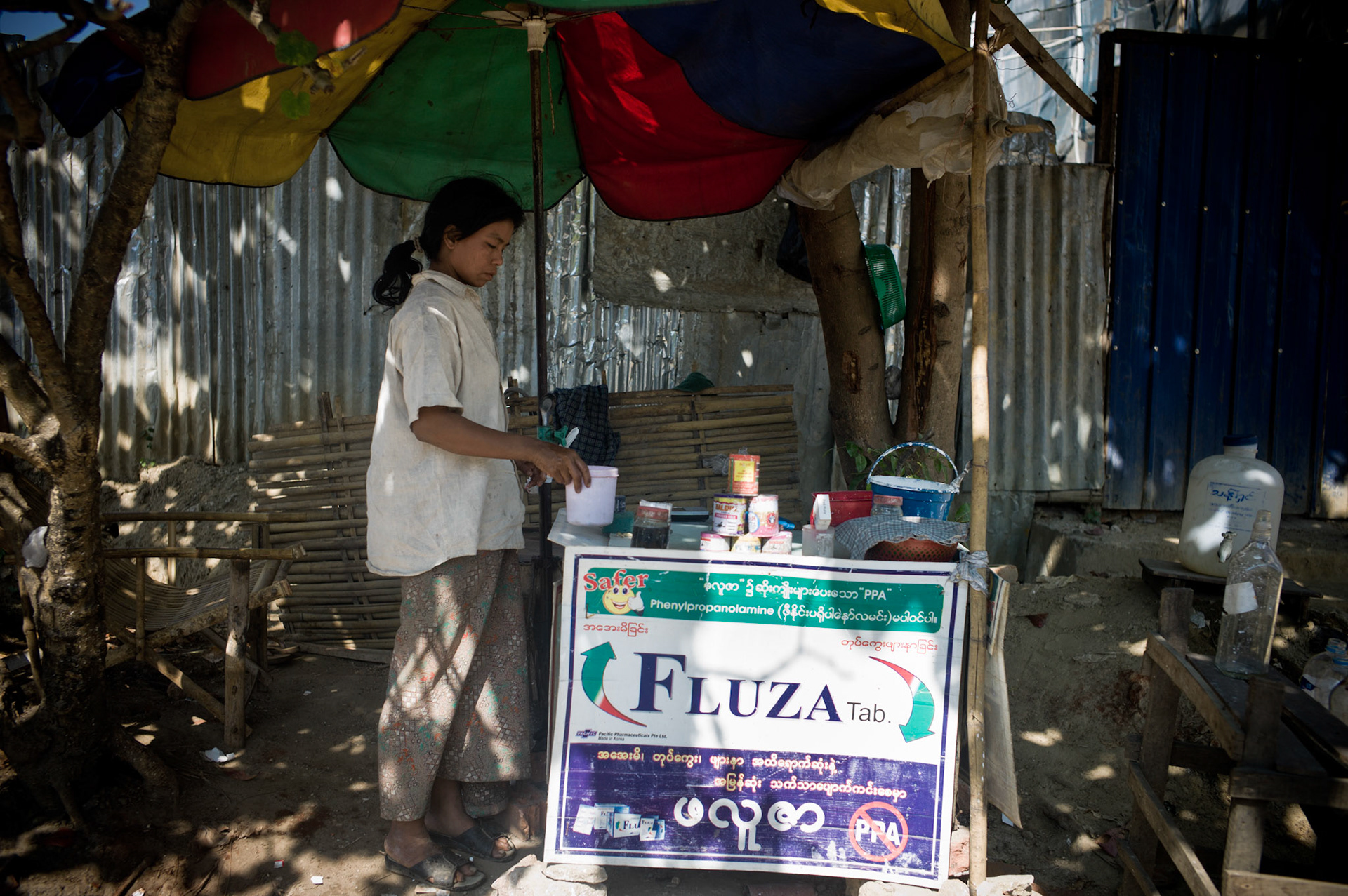 Under the cover of a street vendor selling betel nut, an informer working for military intelligence monitors people walking towards the headquarters of the National League for Democracy. As they walk ast she calls the intelligence officers who are posted outside the NLD office so they can be ready to photograph those who enter. The pervasive nature of fear runs deep in Burma, where informers sit watching at every street corner