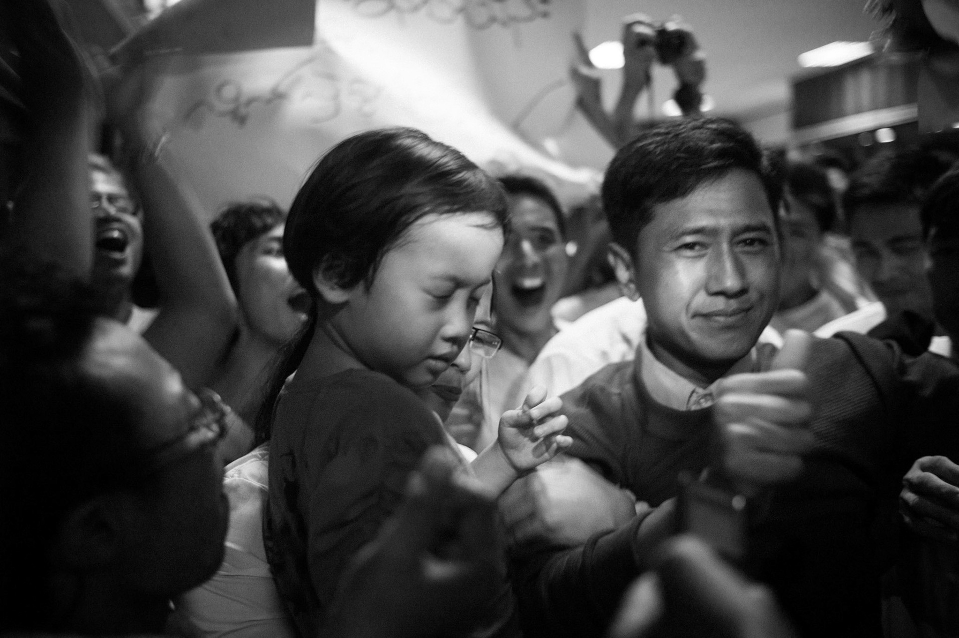 Crowds overwhelmed with joy mob leading Burmese political dissidents Ko Jimmy and his wife Nilar Thein as they are re-united once again with their daughter having both just been released from the 65 year prison sentences they were serving. The Presidential amnesty saw more than 600 political prisoners released from prison, many of who were former leaders of the mass democracy uprising in 1988 and were serving long sentences of 65 years or more.