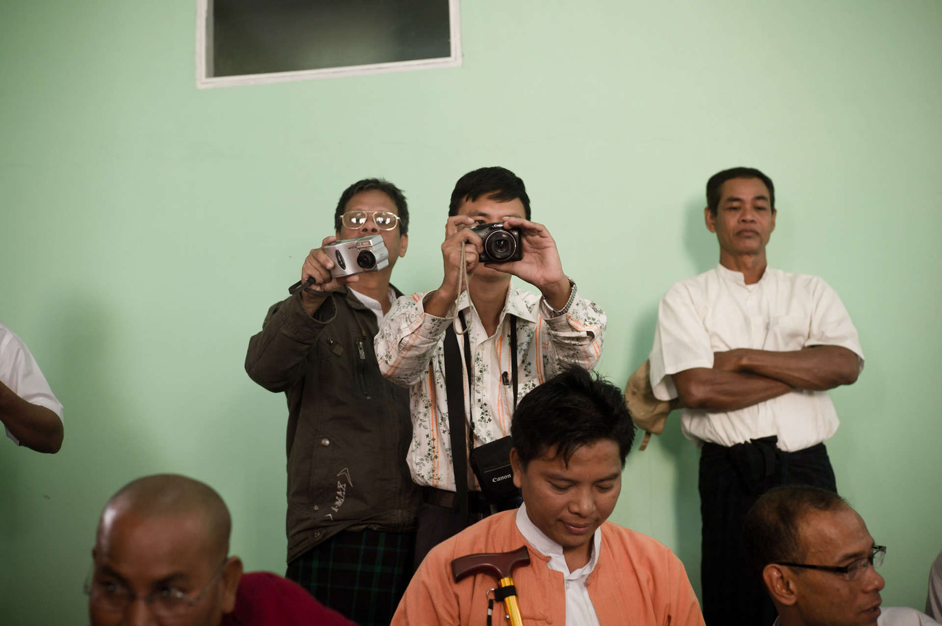 Plain clothed Military Intelligence officers photograph political dissidents and opposition party members including the 88 Generation Students and leading members of the National League for Democracy at a ceremony being held in a monastery in Rangoon. Underneath the veil of the new Burmese Government's democratic change the oppressive nature of the previous military regime continues unabated in Burma