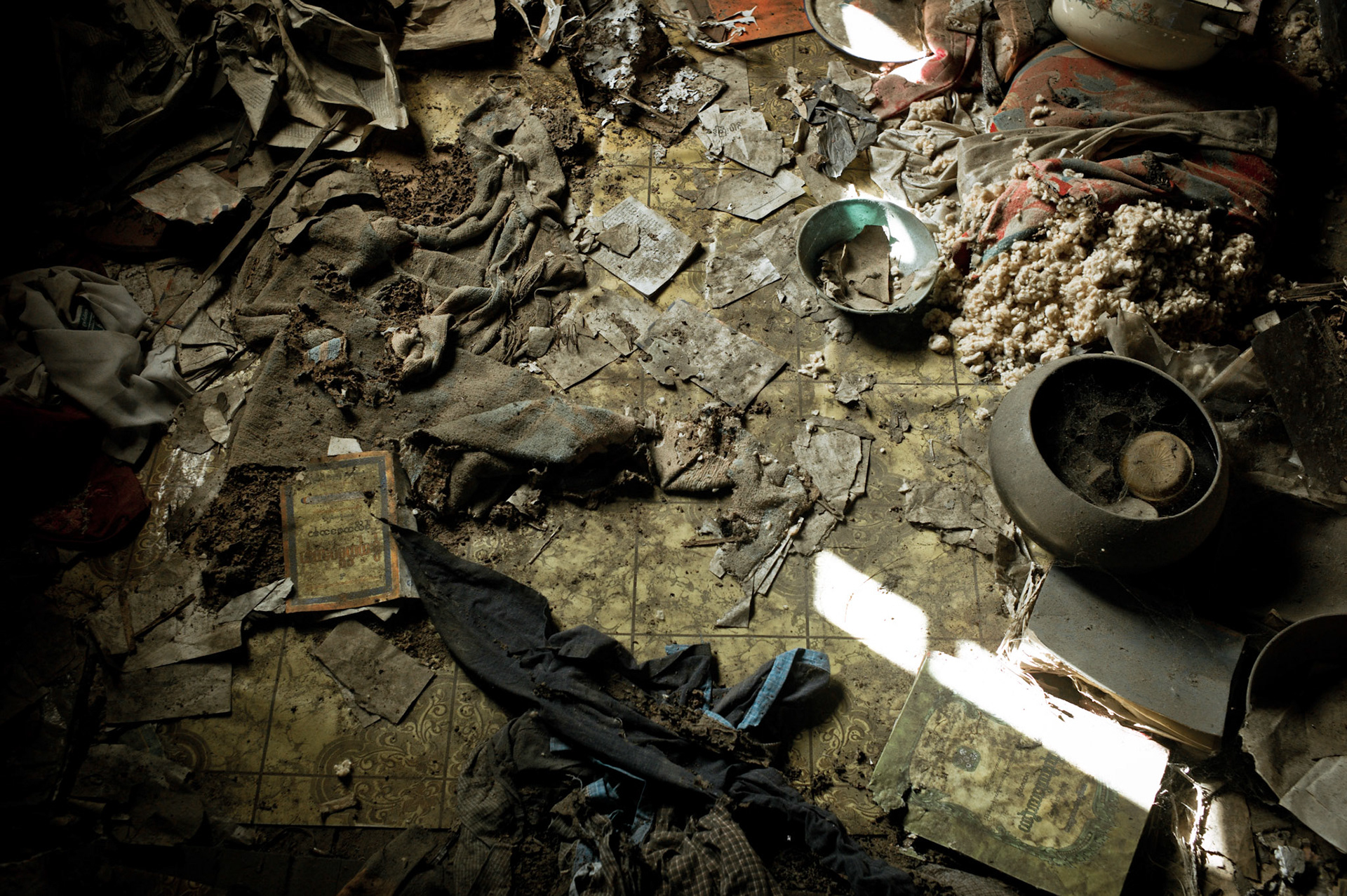Clothes and religious books torn into pieces lie scattered on the floor of the monastery. On September 26th 2007, at the height of Burma's monk led Saffron Revolution, Maggin Monastery in Rangoon, was raided as the regime commenced its brutal crackdown on the protests. On 13th January 2012 the monks were released from prison and more than four years since the monastery was raided and locked, they returned and opened the doors once more. Everything they found was exactly as it was left the night the military regime arrested them and ransacked the buildings.