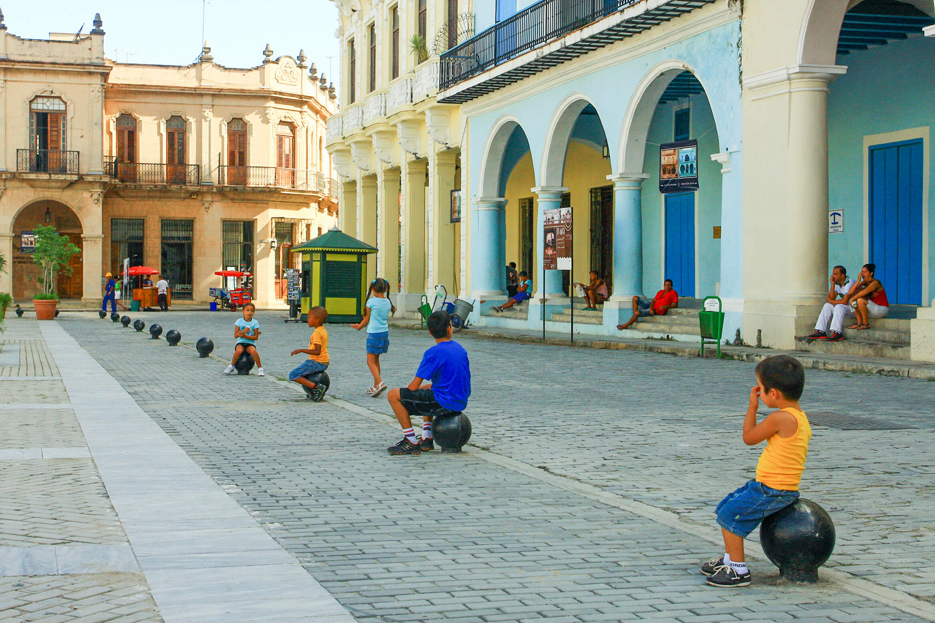 Children sit on decorative cannonballs in Havana.