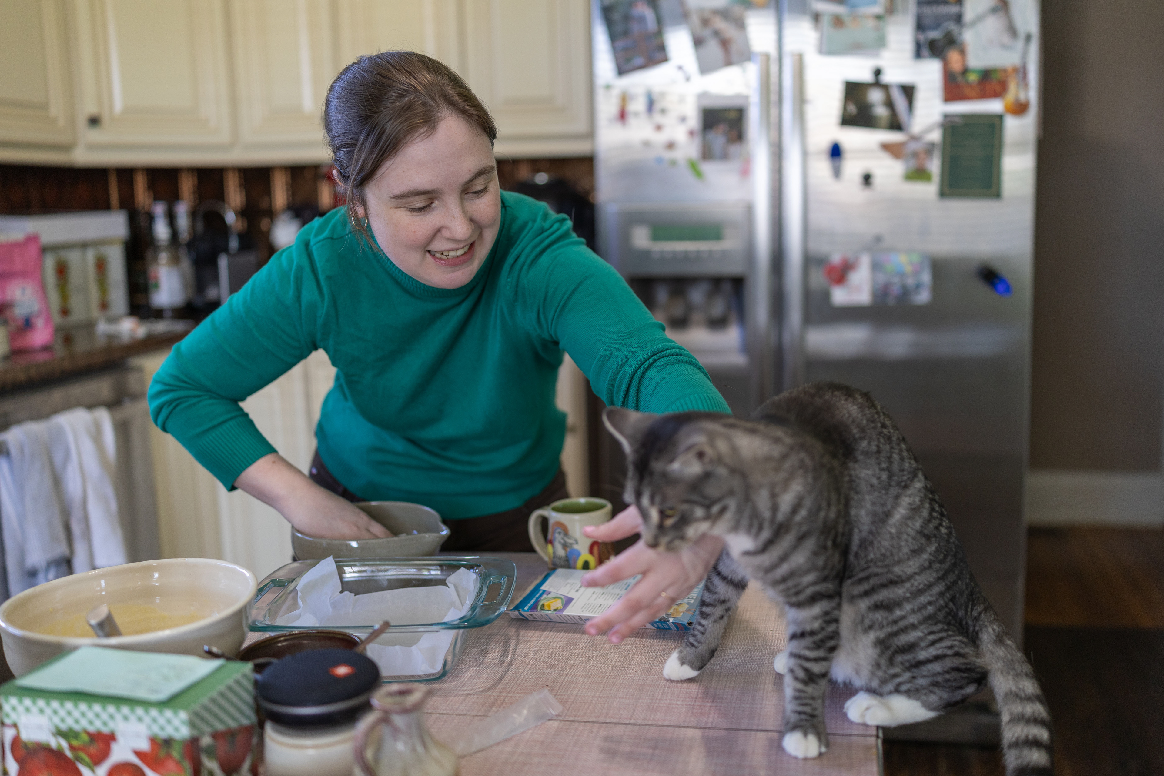 Erin pushes away one of her three cats, Huey Lewis, while making lemon bars at her house for an event she was hosting the next day.