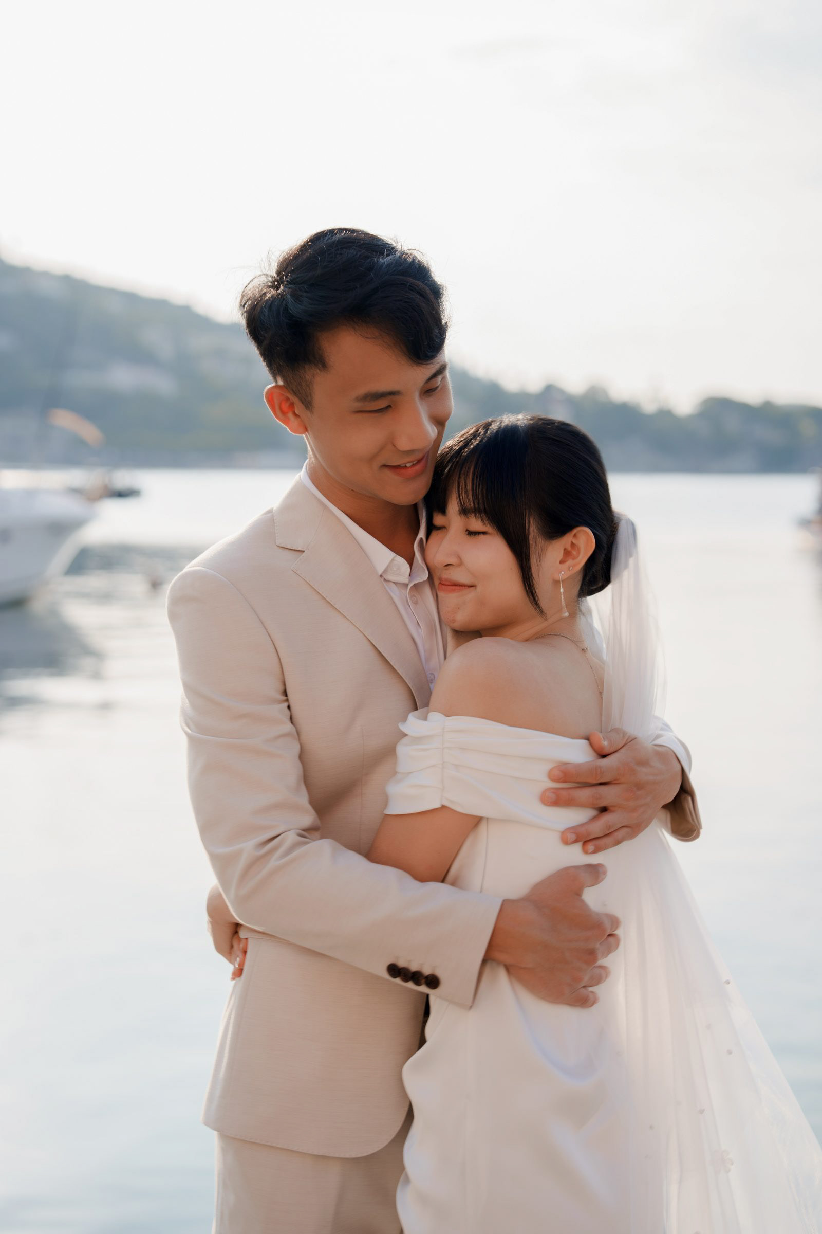 Groom holding his fiancée close by the water