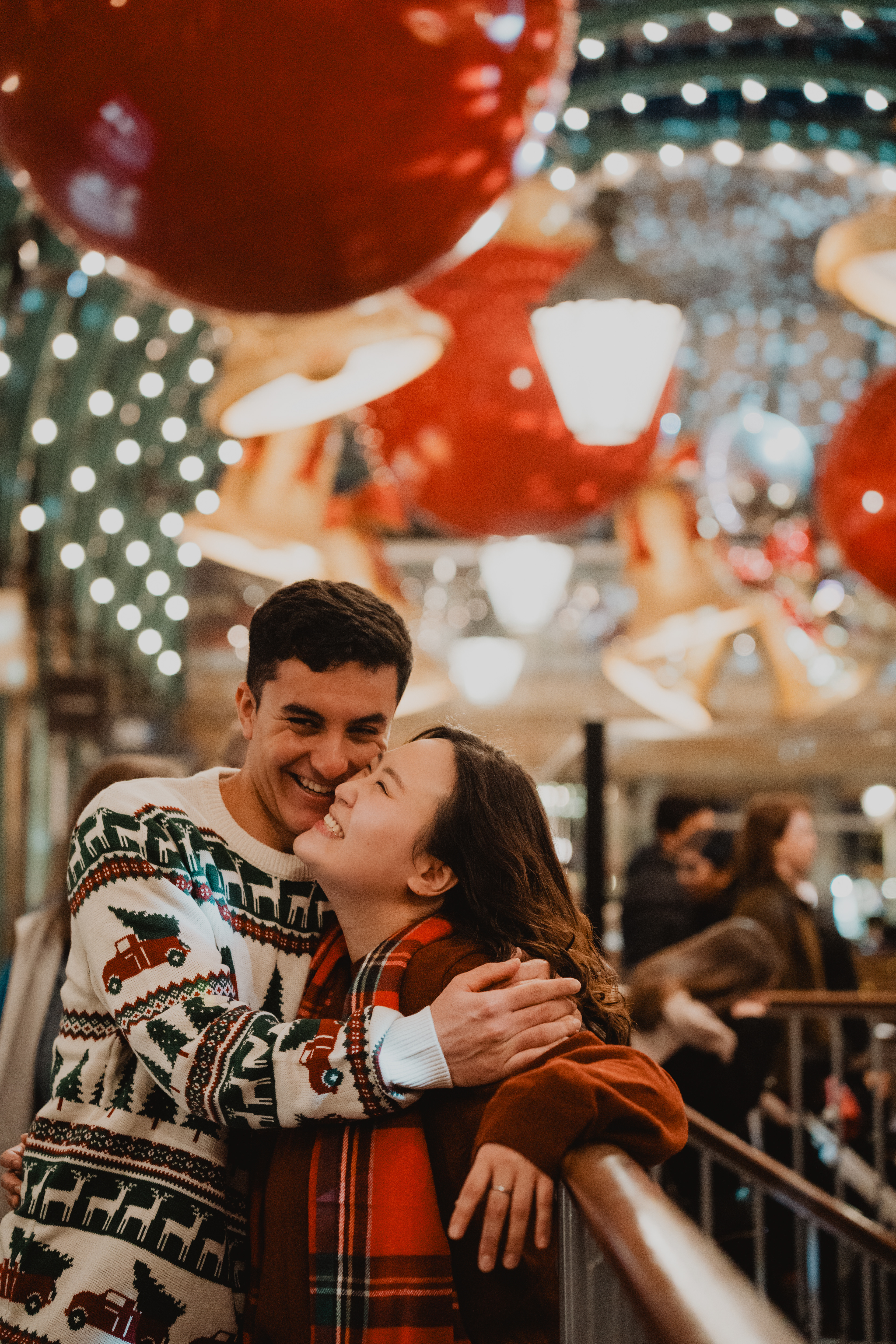 Close-up of couple beneath Covent Garden giant Christmas baubles, London