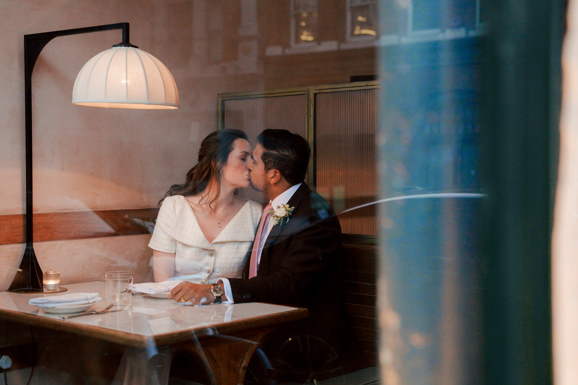 Bride and groom sharing a kiss at a window table at Luca, Clerkenwell