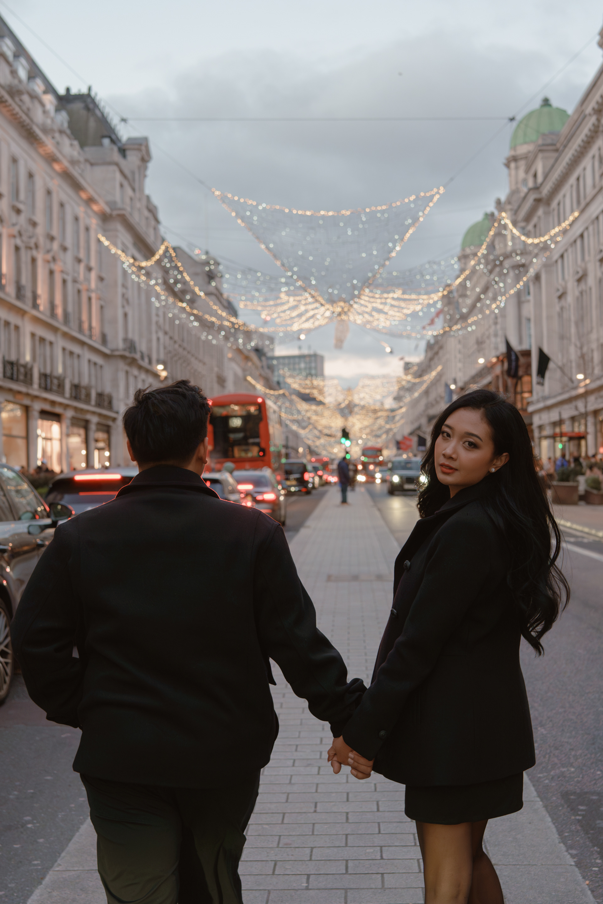 Close-up of couple with Regent Street Christmas angels overhead, London