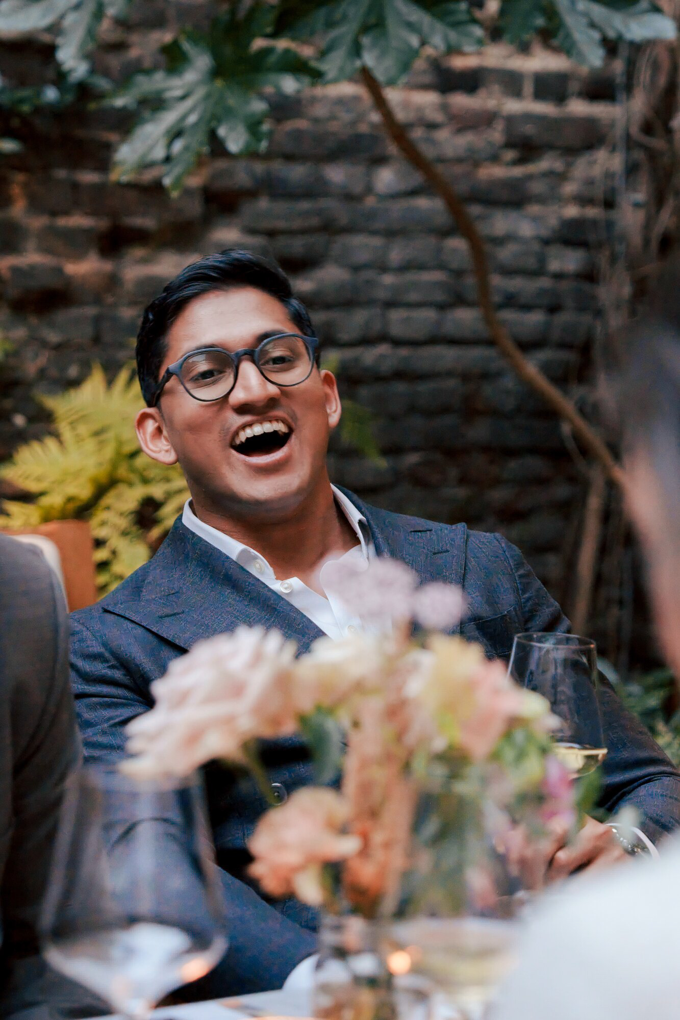 Wedding guest laughing during dinner in the courtyard at Luca, London