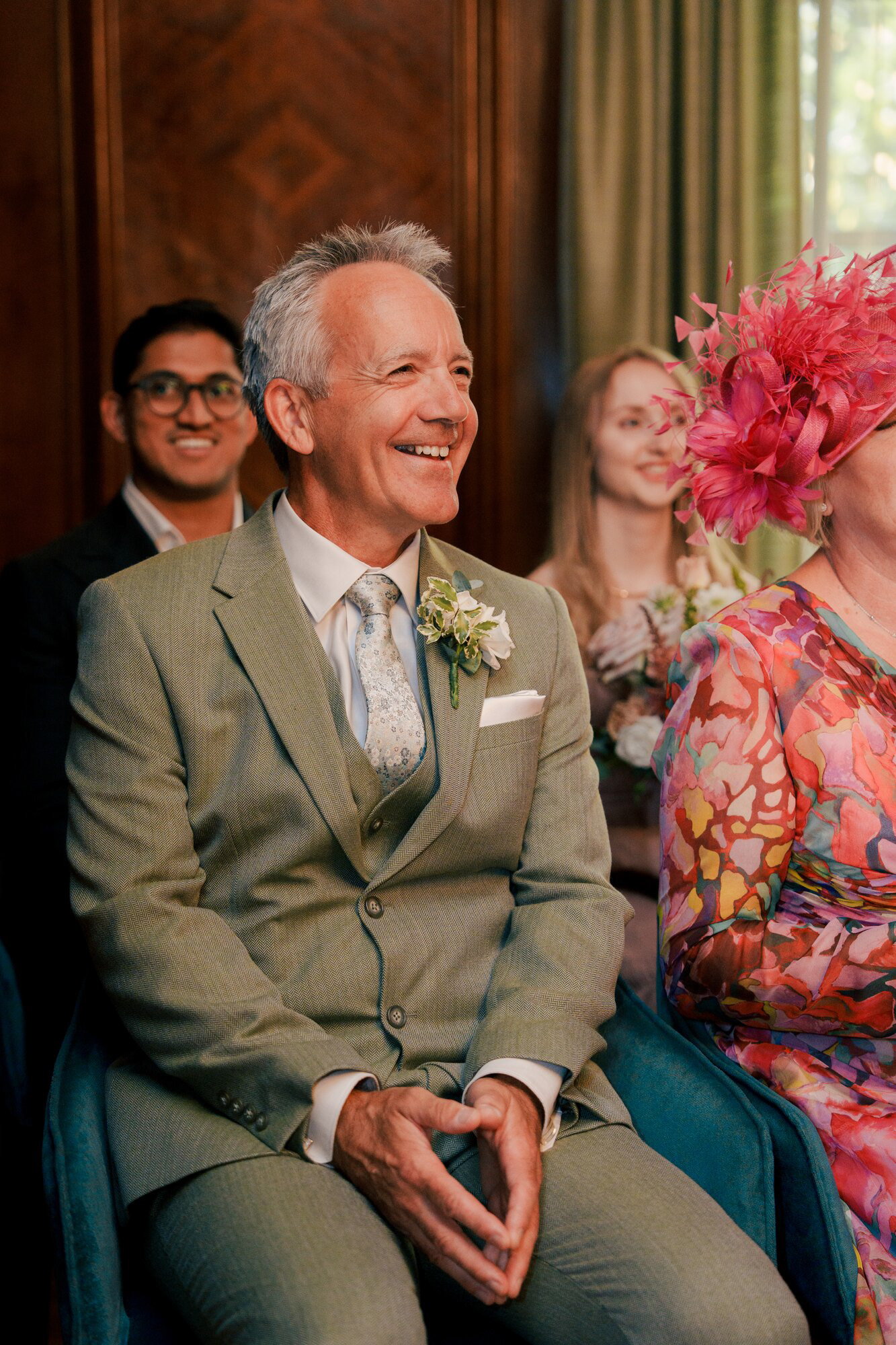 Guest in a sage green suit smiling during the civil ceremony at Old Marylebone Town Hall