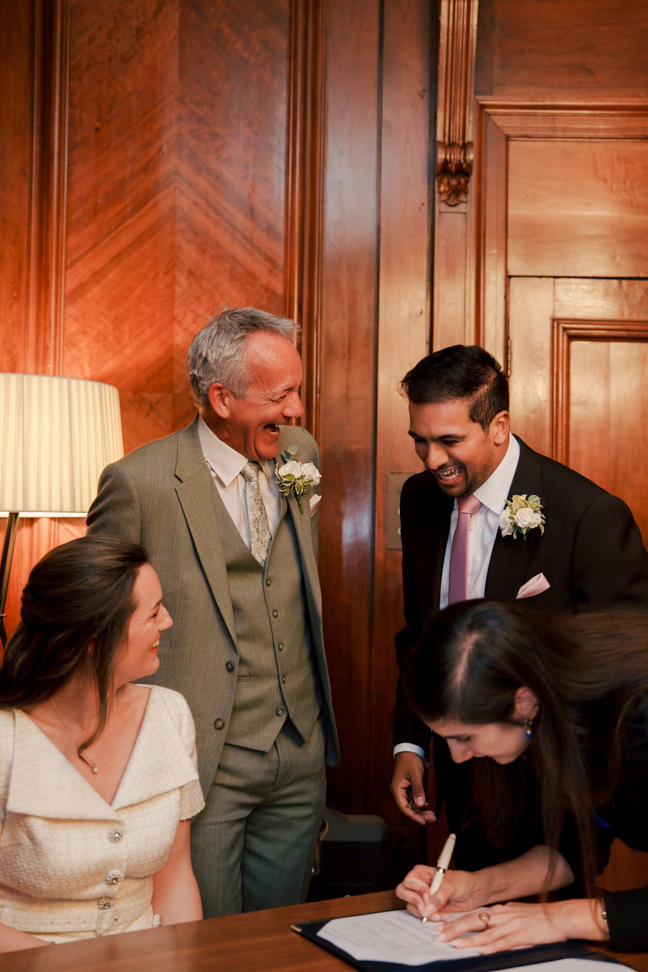 Registrar completing the marriage paperwork as the couple and family laugh