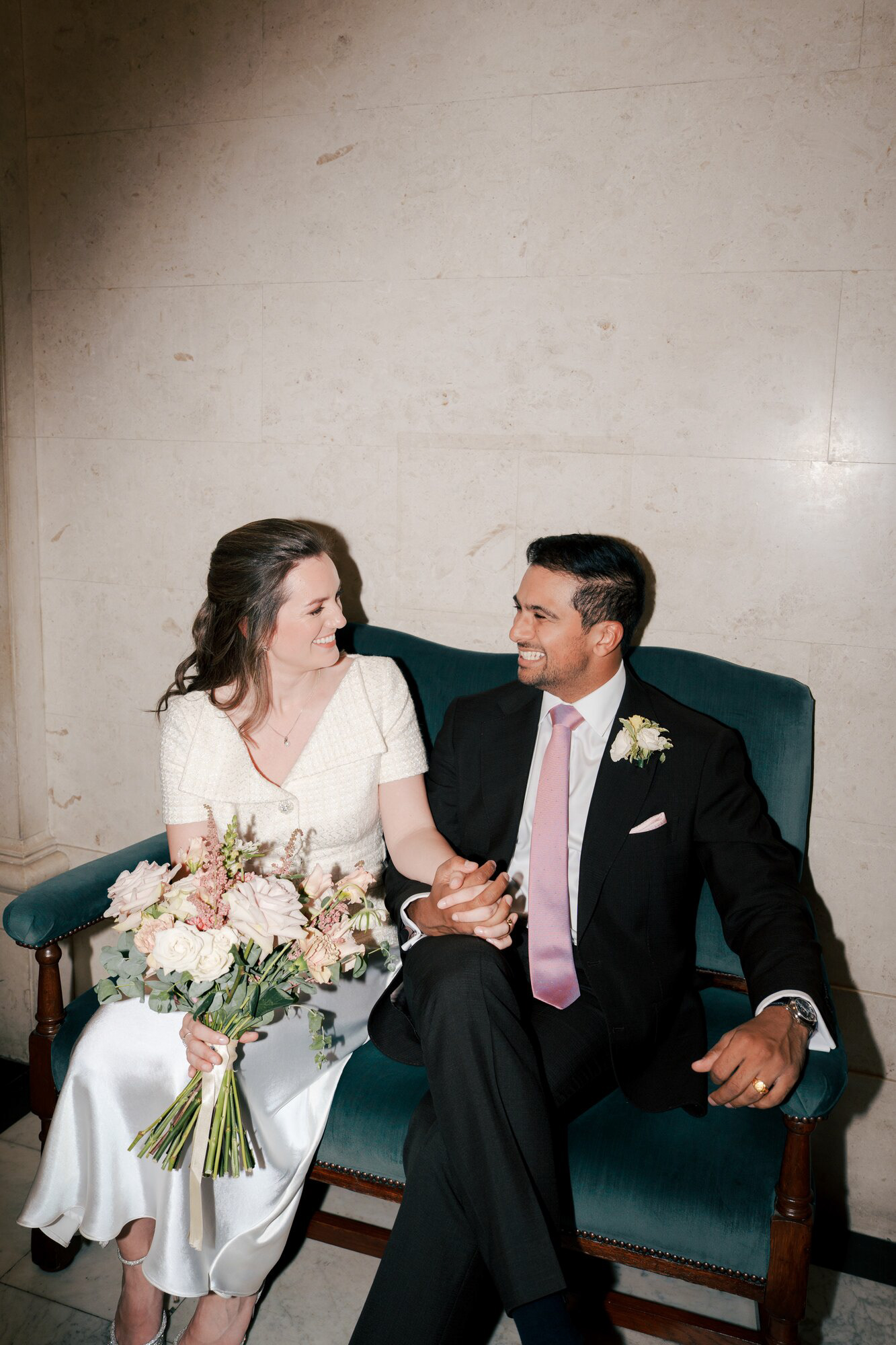 Flash portrait of the bride and groom on a velvet bench inside Old Marylebone Town Hall