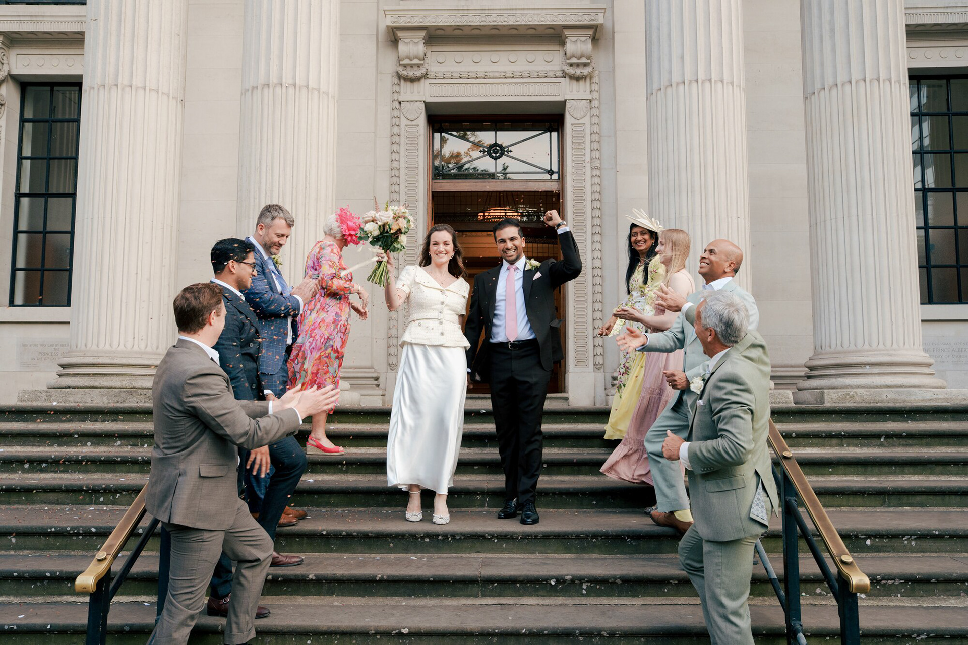 Friends and family cheering the newlyweds on the steps of Old Marylebone Town Hall