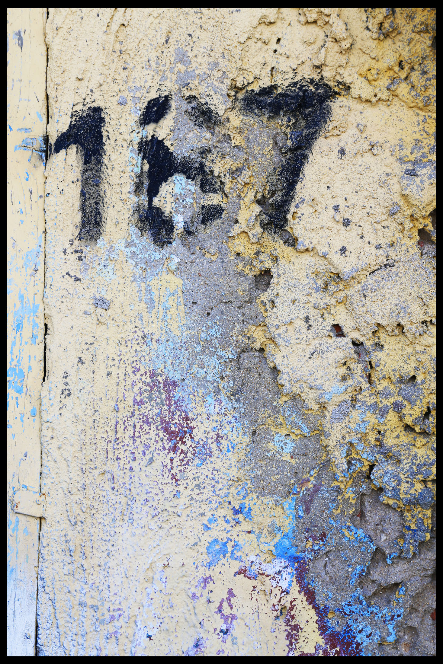 Mur en peinture jaune avec des marques de peinture bleue, montrant une texture complexe.