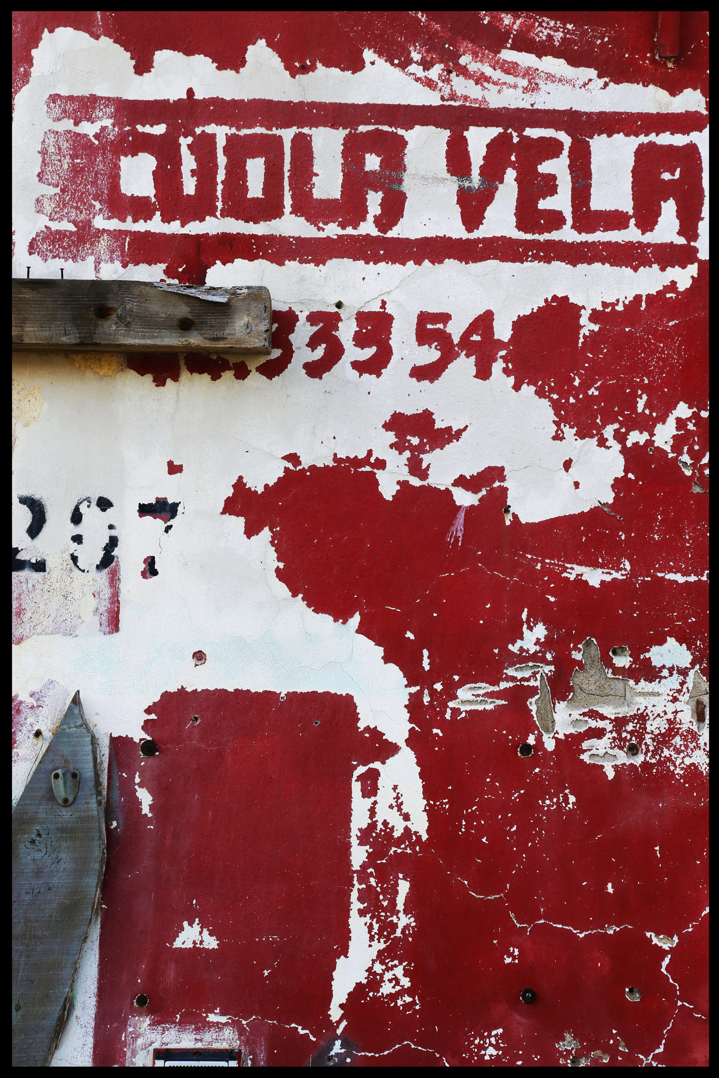 Mur rouge écaillé avec des chiffres et des marques, illustrant l'usure.