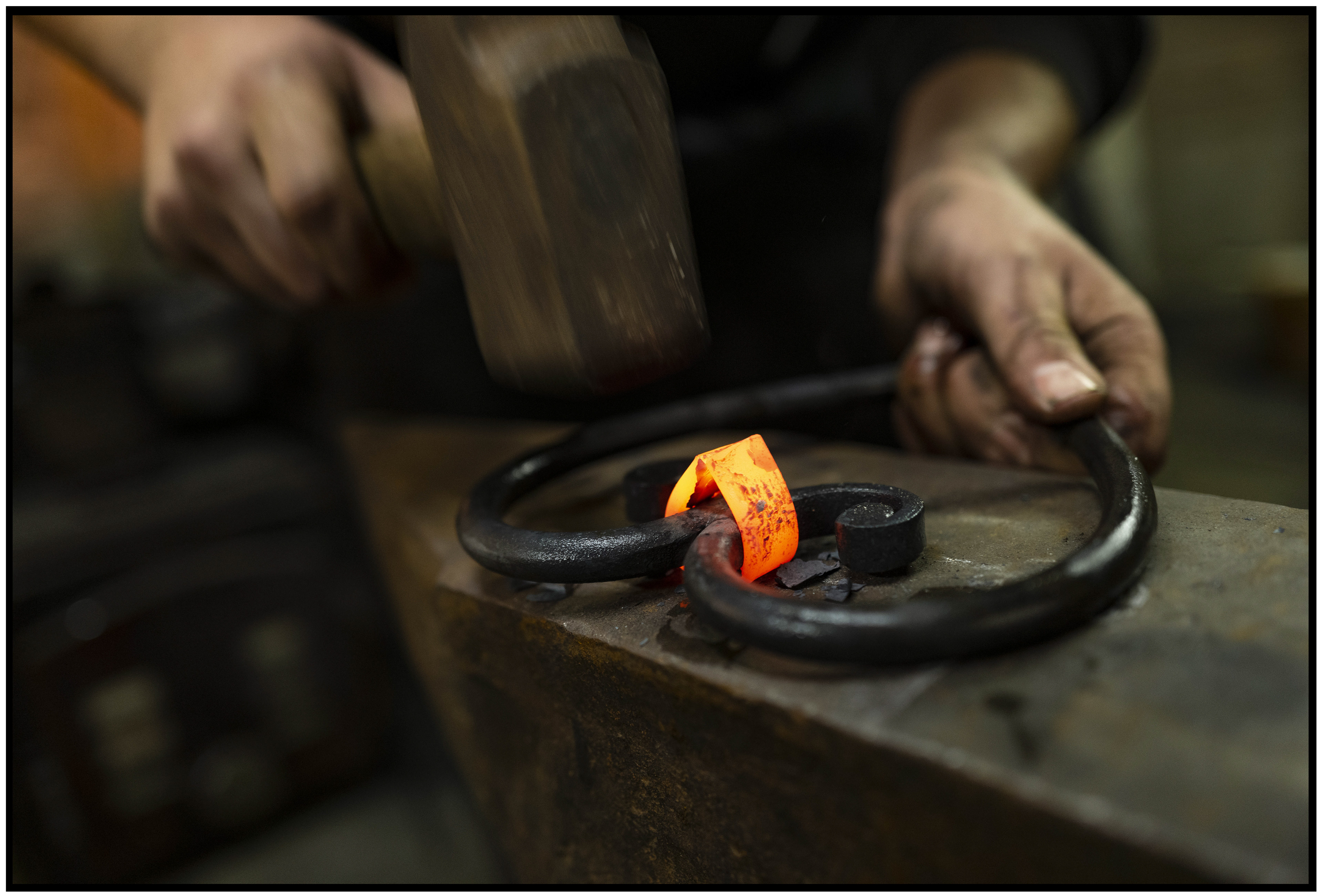 Cœur en métal, partiellement incandescent, accompagné d'un marteau, capturant l'intensité du travail de forge.