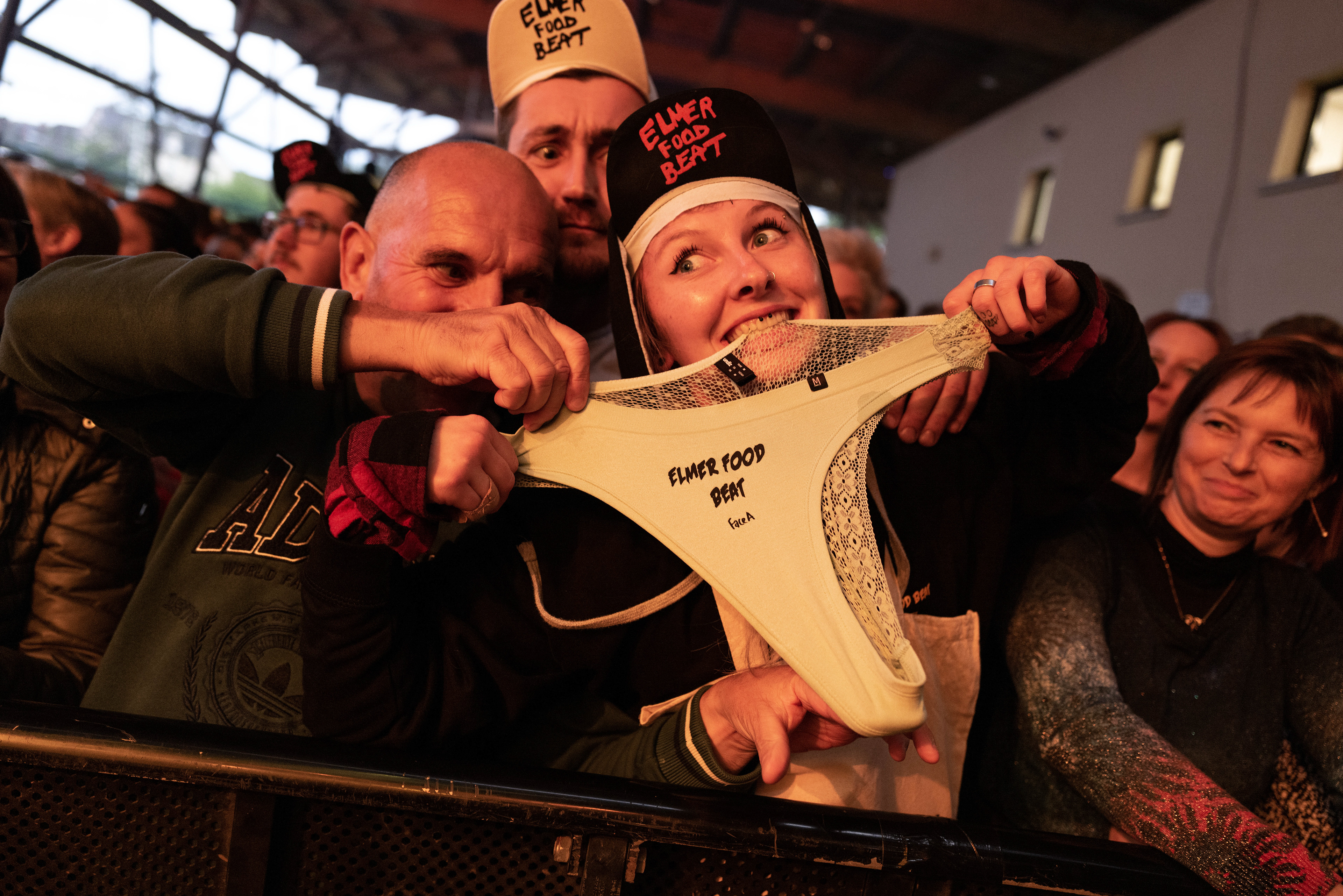Festivaliers souriant et tenant un sous-vêtement marqué 'Elmer Food Beat' lors du festival.