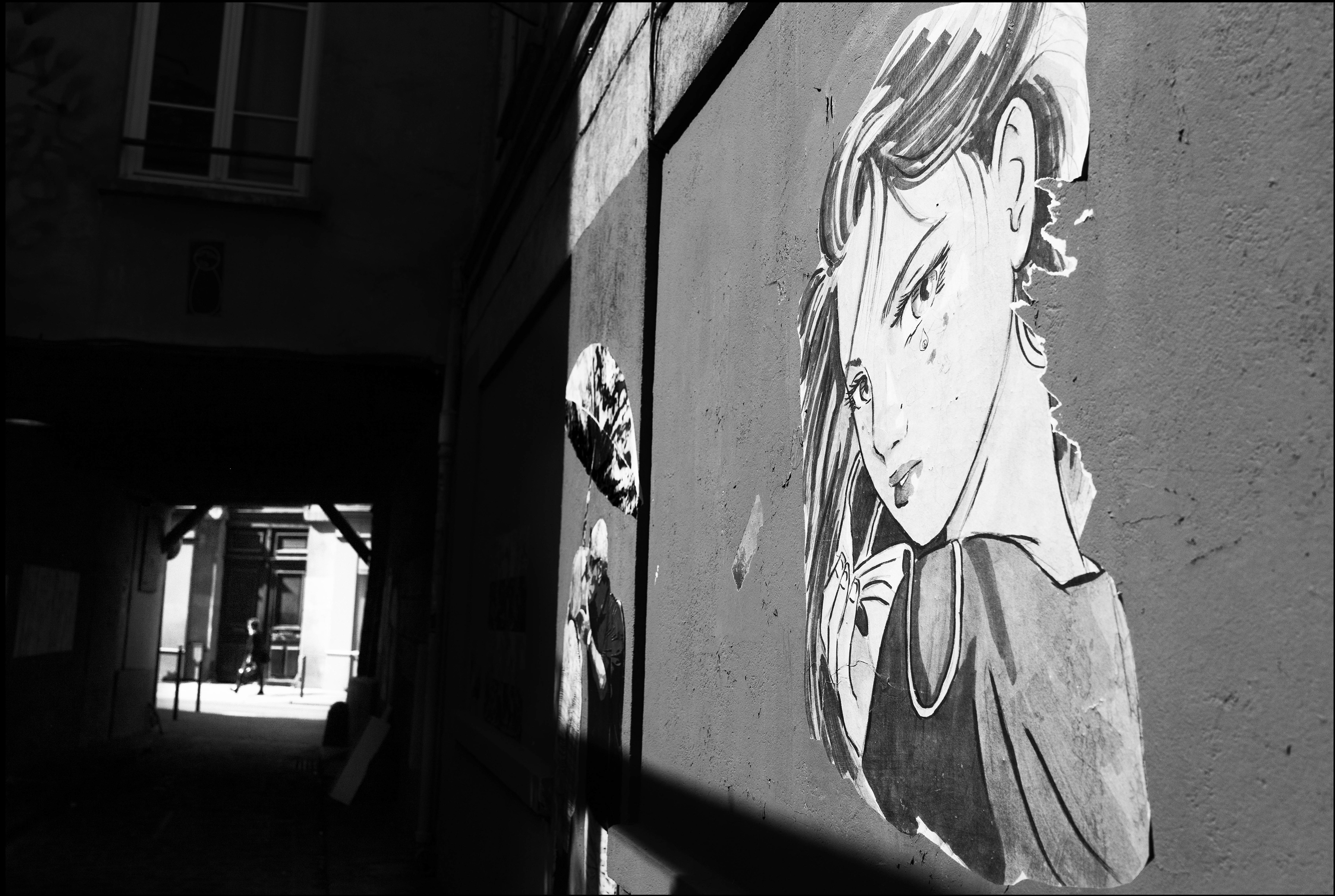 Portrait d'une femme sur un mur dans une ruelle à Paris, avec des jeux d'ombre et de lumière.