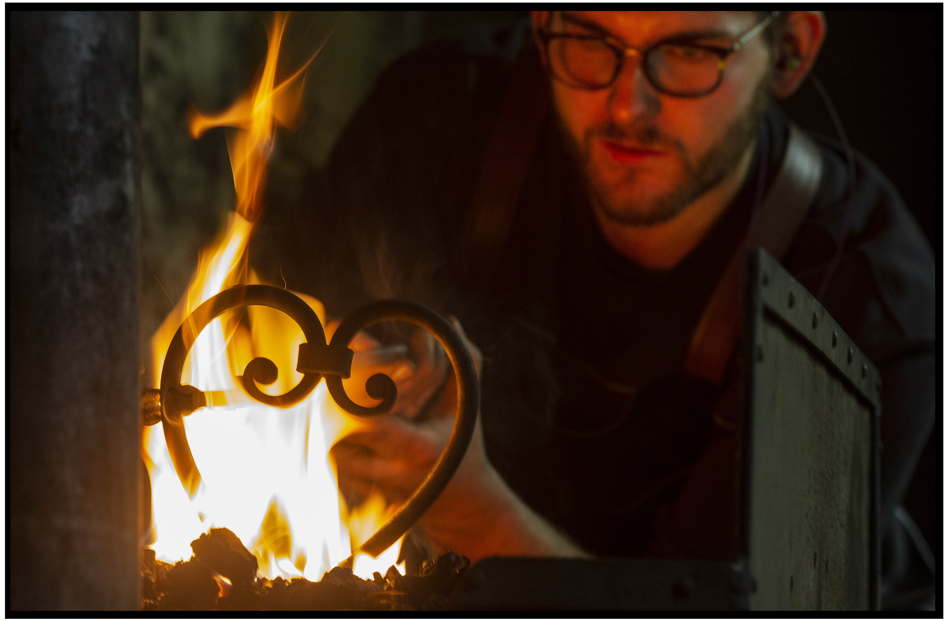 Forgeron en arrière-plan, finalisant un cœur de métal forgé à la main dans le feu.