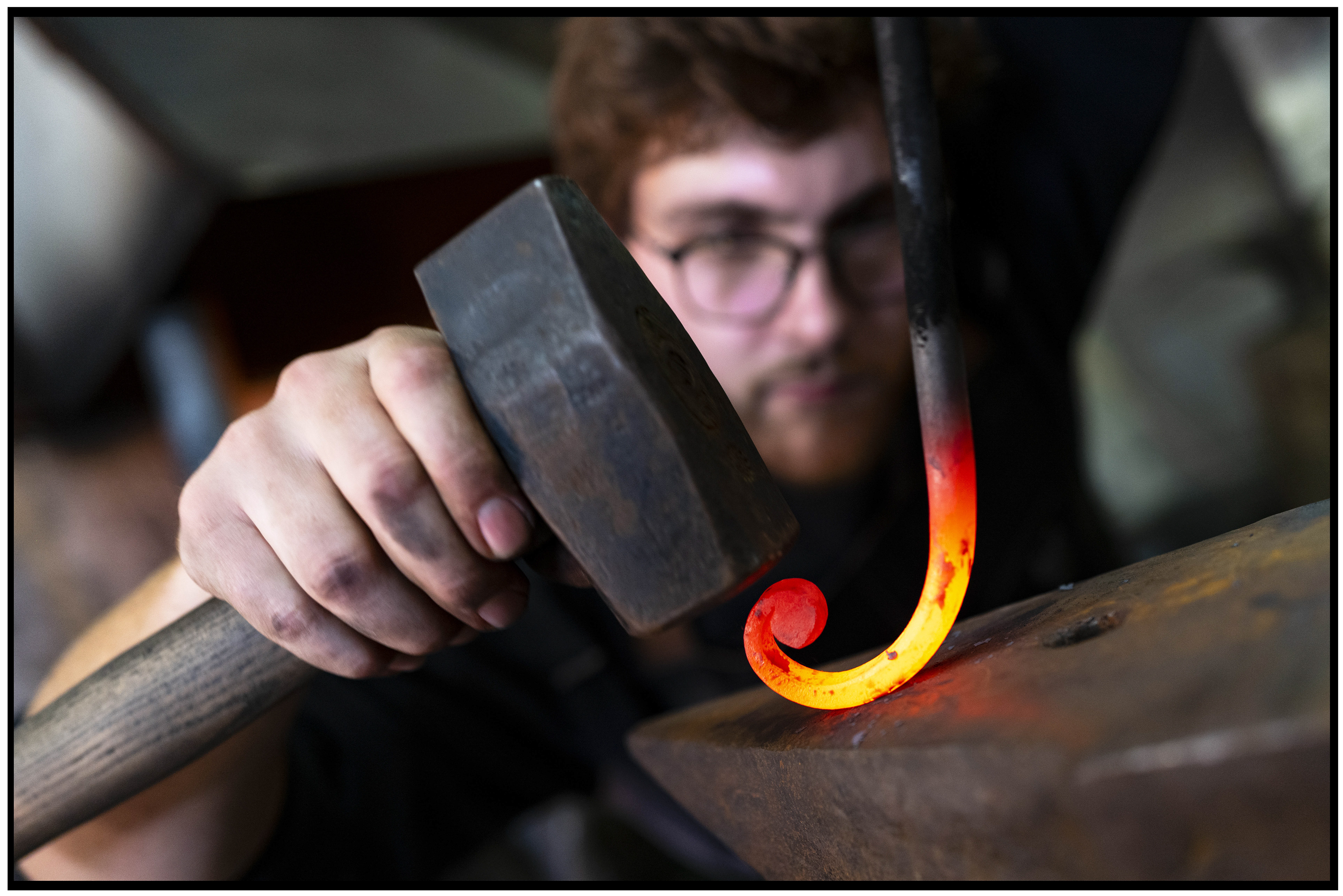Jeune forgeron travaillant le métal rougi pour réaliser des courbes, capturant l’essence de l’artisanat