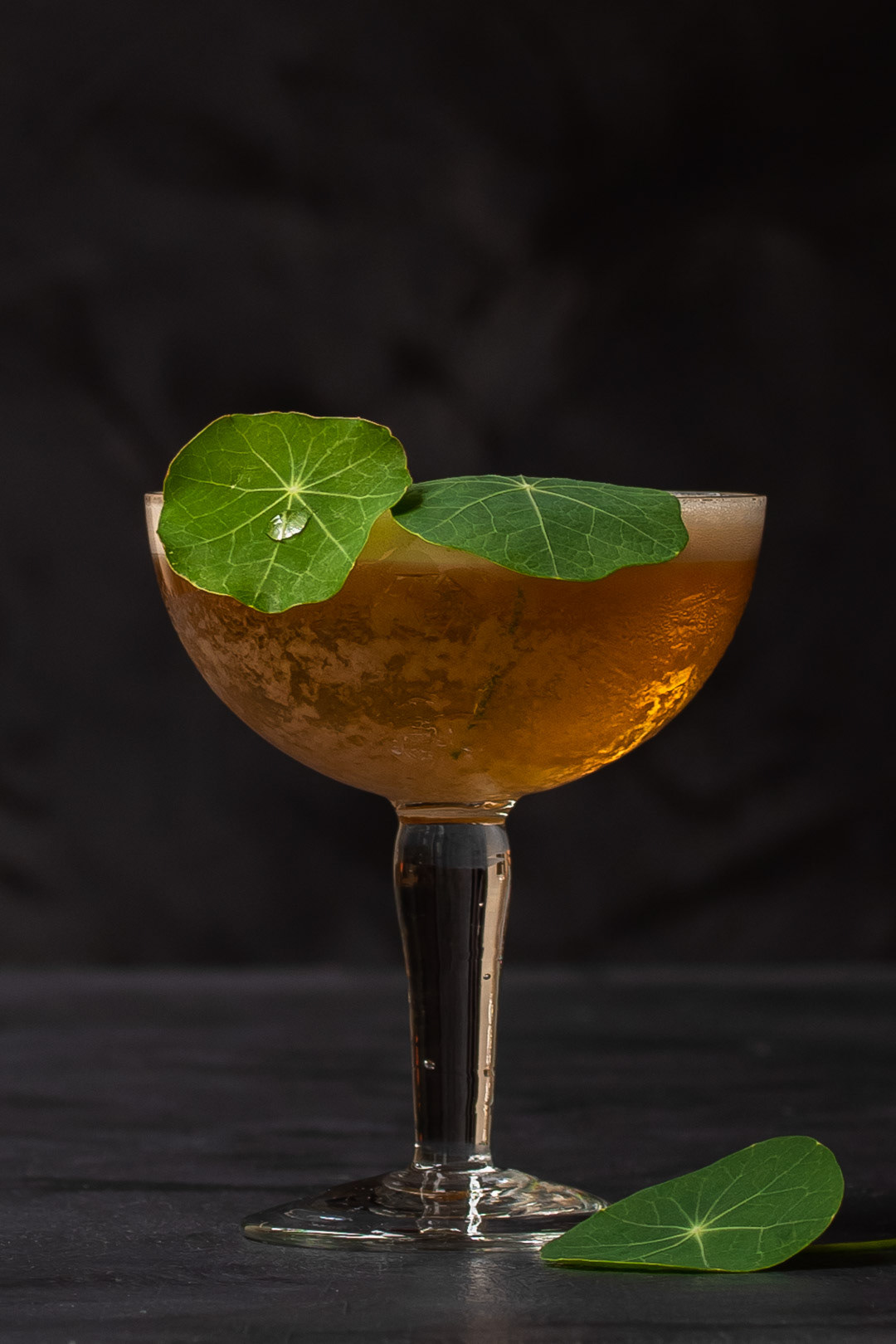 honey rhubarb silver sour with nasturtium leaf with water drop garnish