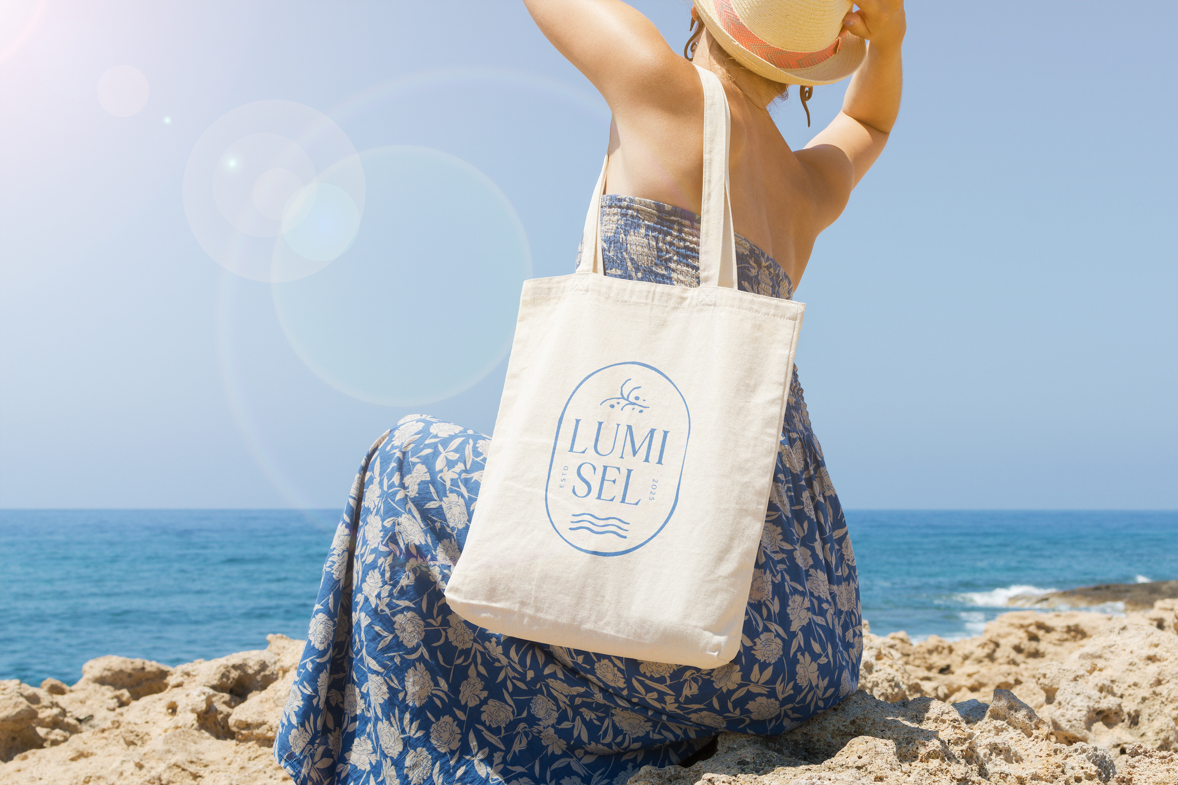 Woman overlooking beach with a canvas tote bag with the vertical Lumisel Logo