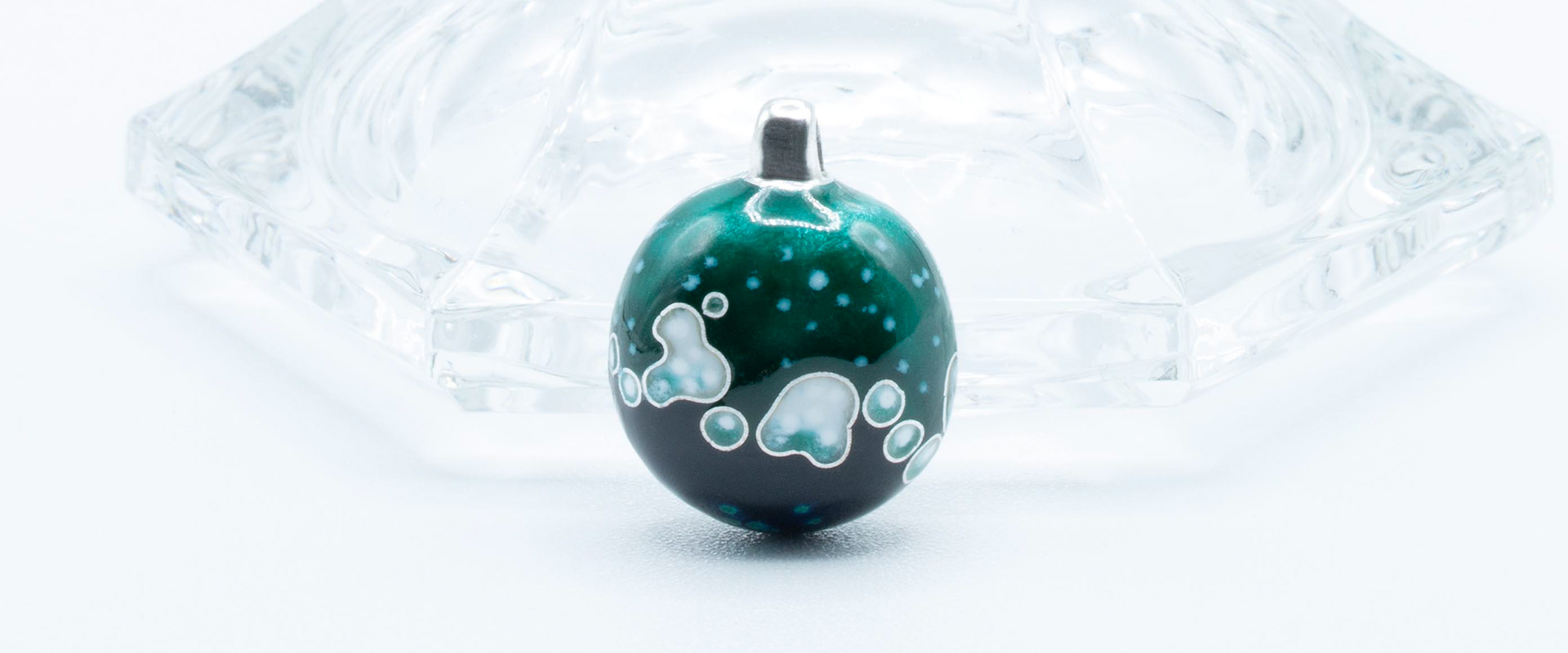 Pendentif artisanal en argent et émail présentant un motif organique vert émeraude, noir, blanc et gris créé selon la technique du cloisonné. Design circulaire bombé avec de délicats contours en fil d'argent.