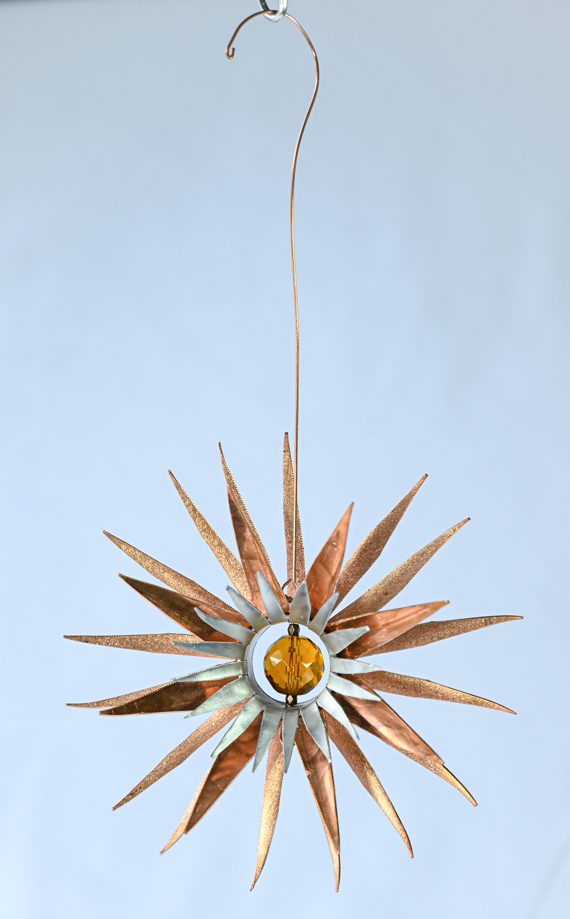 "Fireworks" looks like it has just exploded! It is a hand-formed copper and aluminum star flower with an amber crystal centre. It measures 5" wide x 2" deep and 9" high (including hanger), $75.