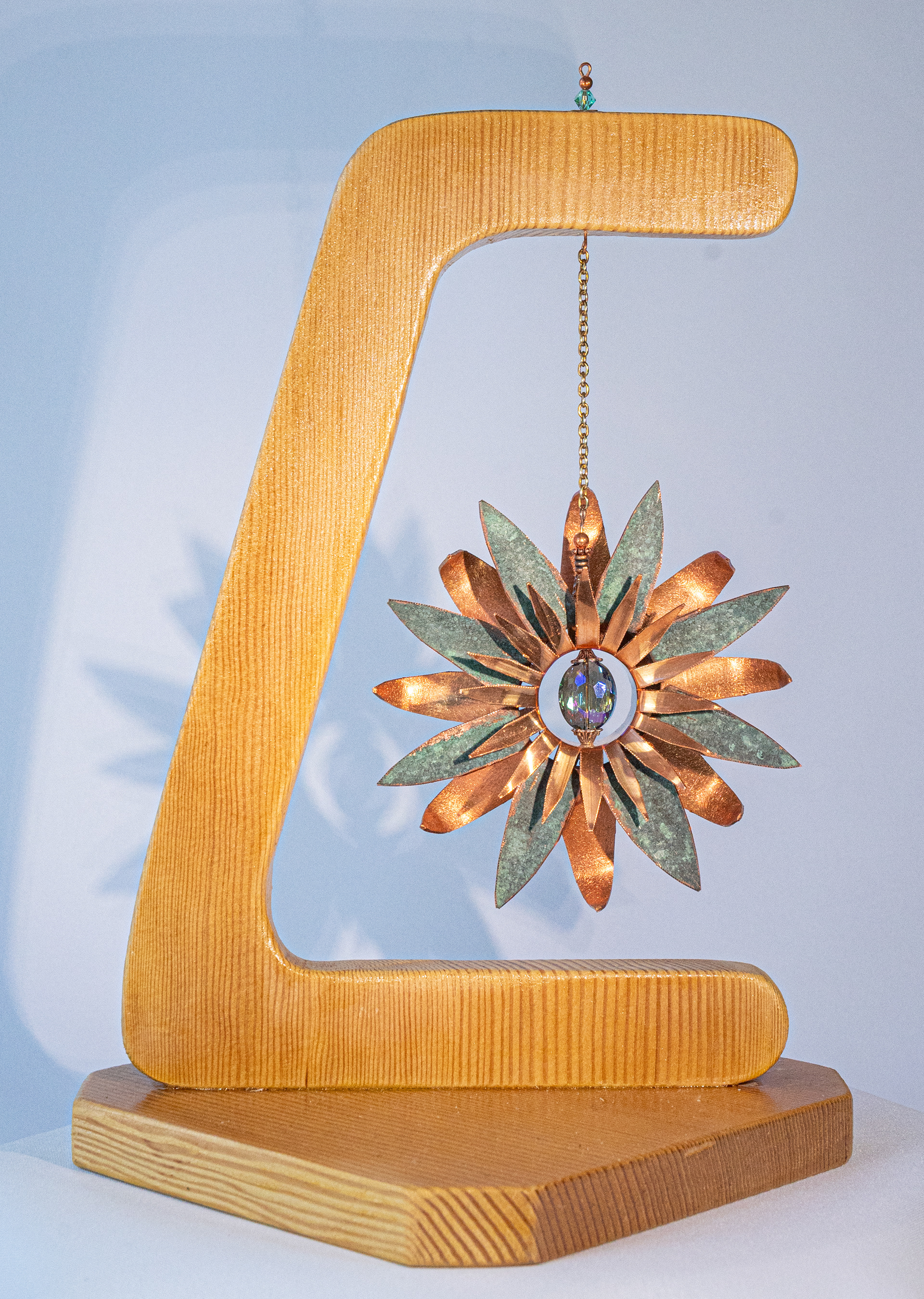 "Patina Star" has a copper flower featuring a natural green patina and a crystal centre hanging by a chain on a fir base,  11.5 inches high x 7 inches wide x 7 inches deep, $175