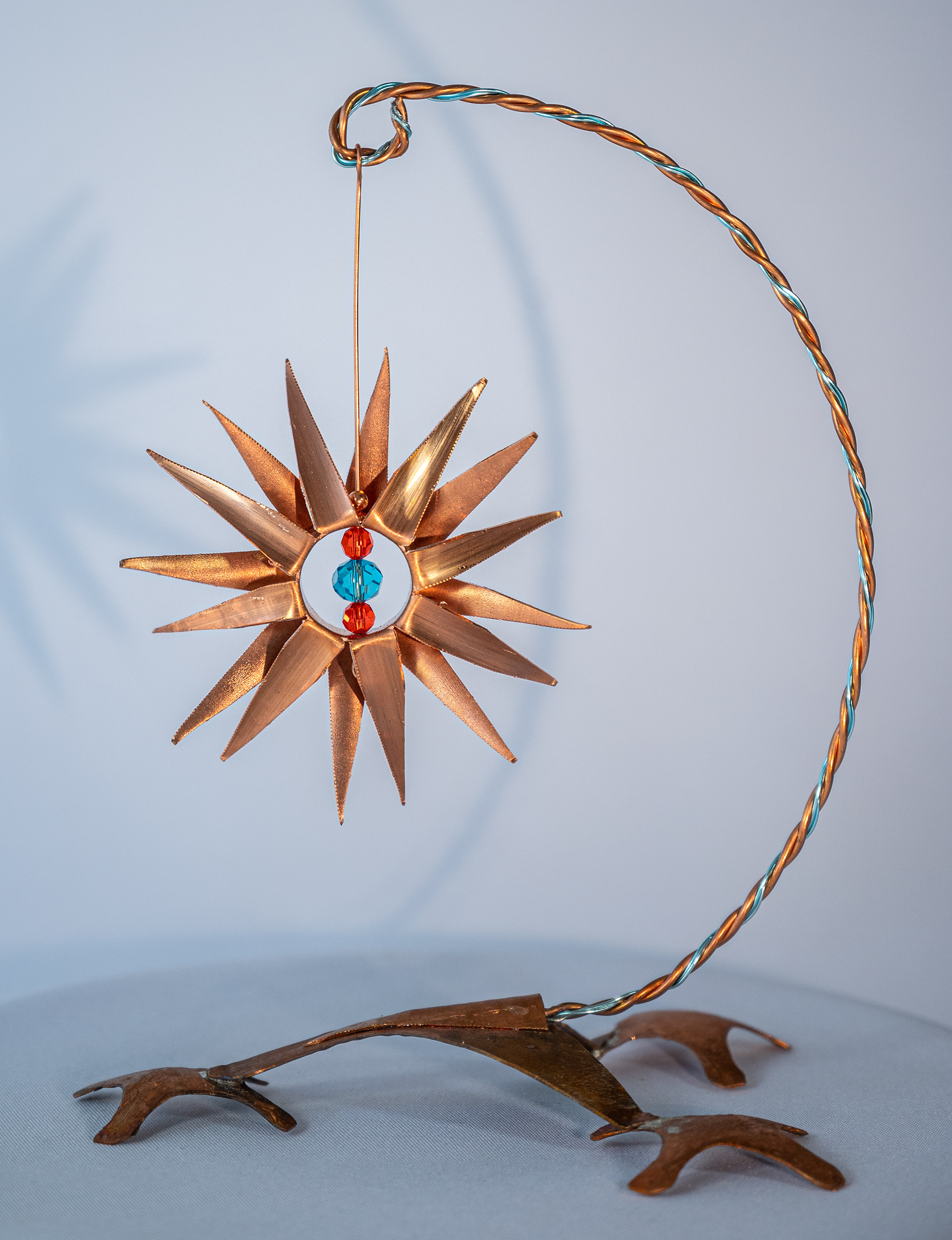 "Tripod" is a copper flower attached to a copper base with hand twisted wire with blue and red crystals, 7.5 inches high x 6 inches wide x 4.5 inches deep, $125
